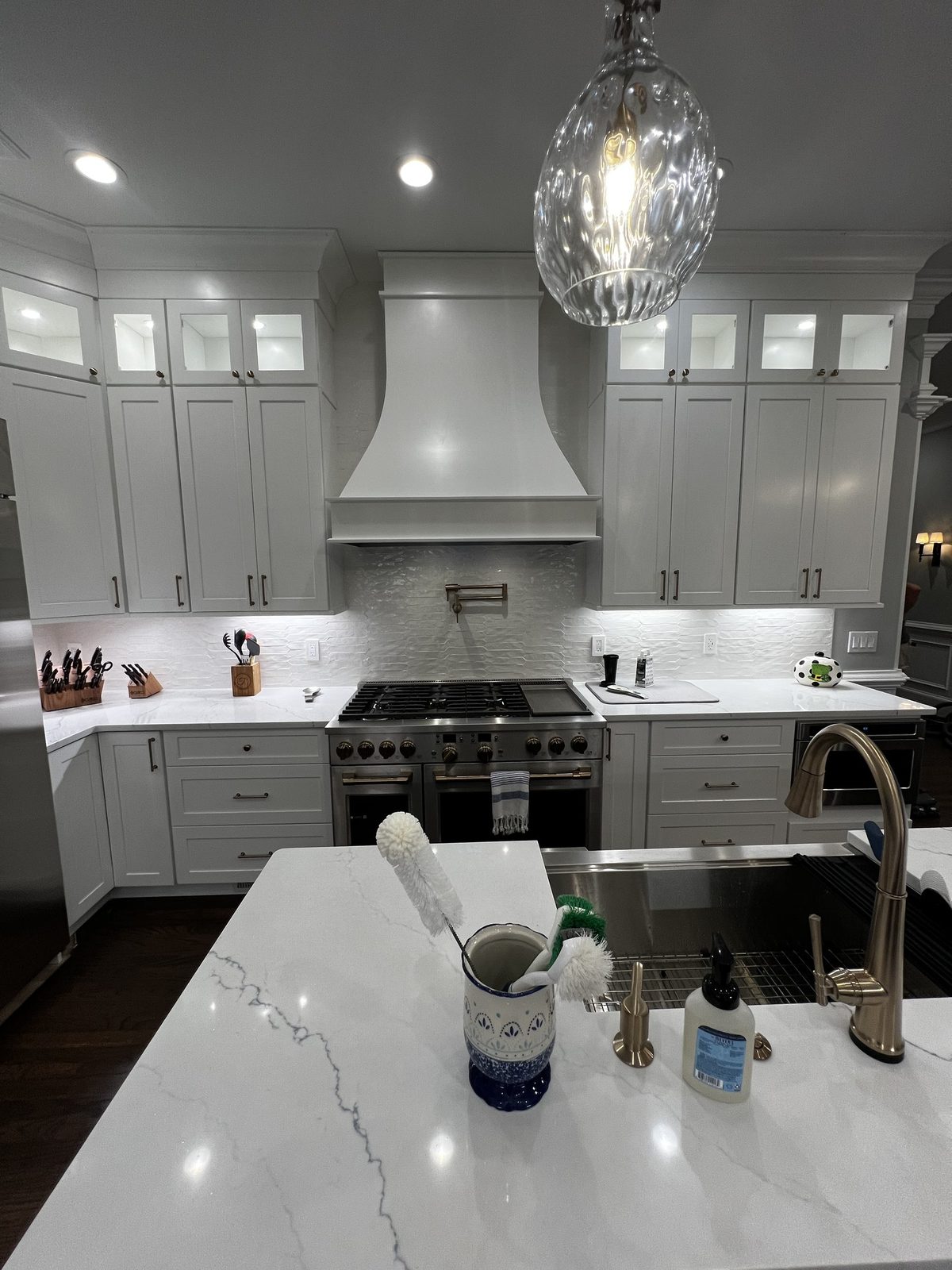 White kitchen with custom range hood and quartz countertops