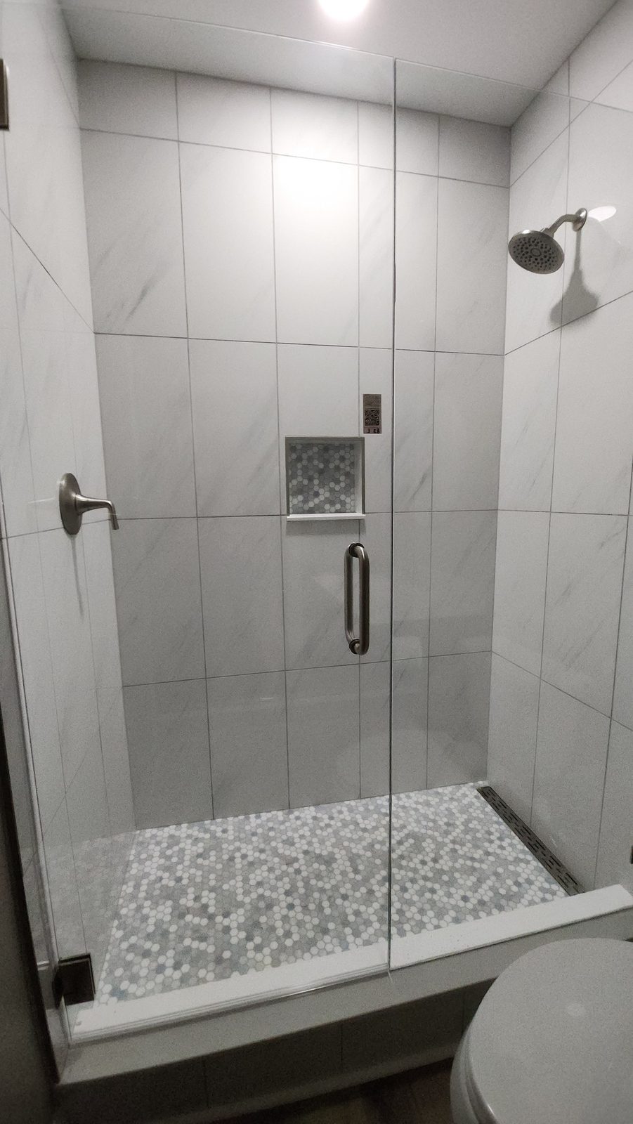 Walk-in tile shower with frameless glass door and pebble floor