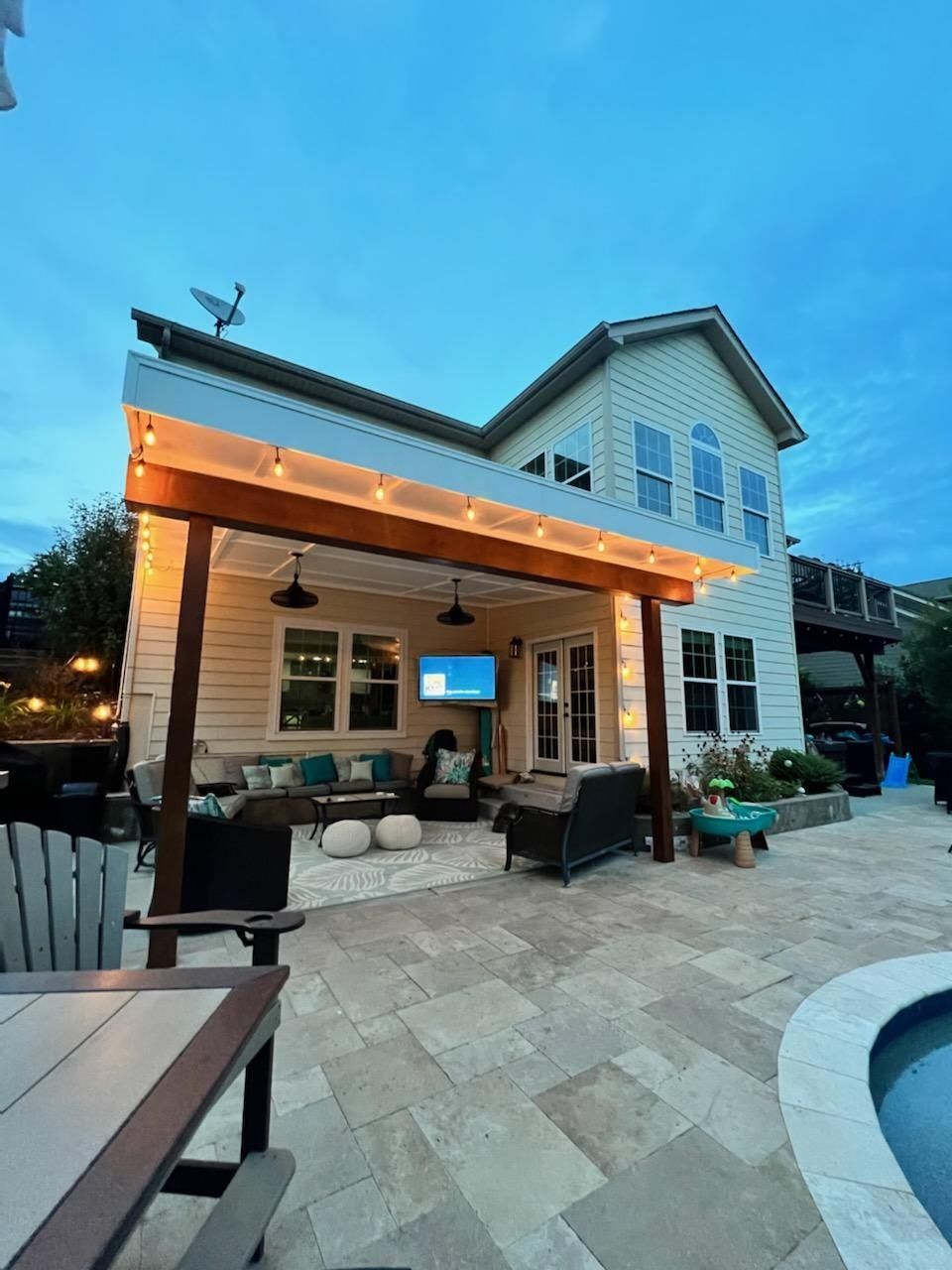 Covered patio with string lights and outdoor living space at dusk
