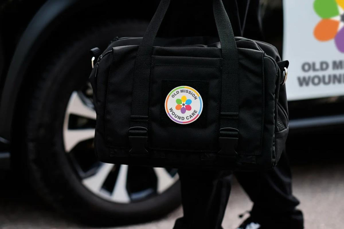 A mobile nurse practitioner carries an Old Mission Wound Care medical bag to an appointment.