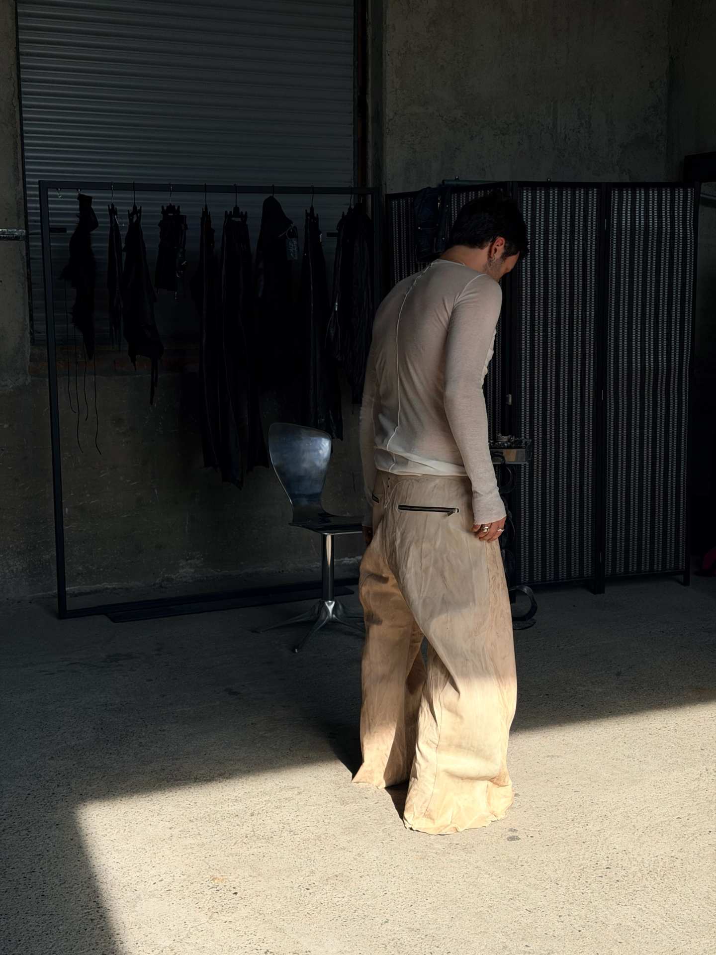 Gli stessi pantaloni visti da dietro, mentre cammina nella luce.