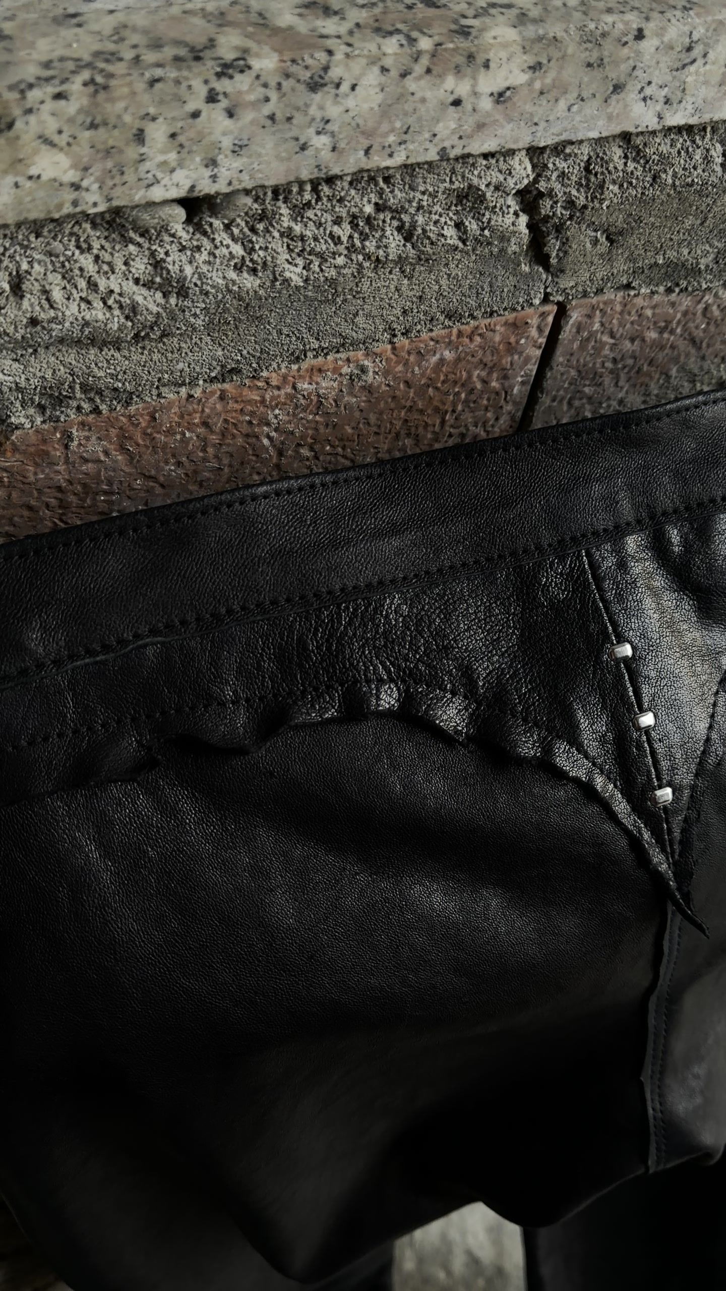 A pan across the raw edge of a leather piece resting on granite.