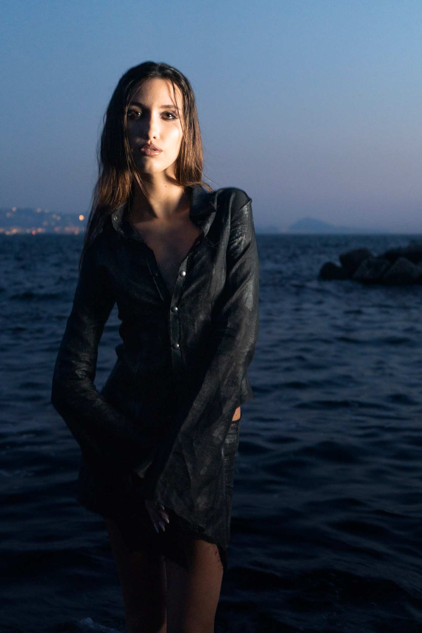 La camicia scura indossata sugli scogli, davanti al mare, alla luce del tramonto.
