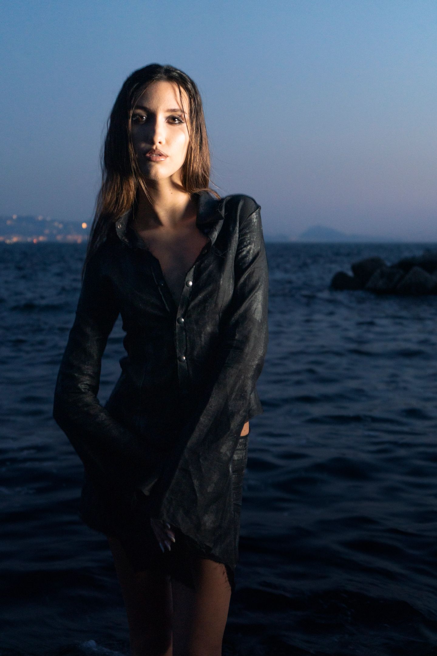 La camicia scura indossata sugli scogli, davanti al mare, alla luce del tramonto.