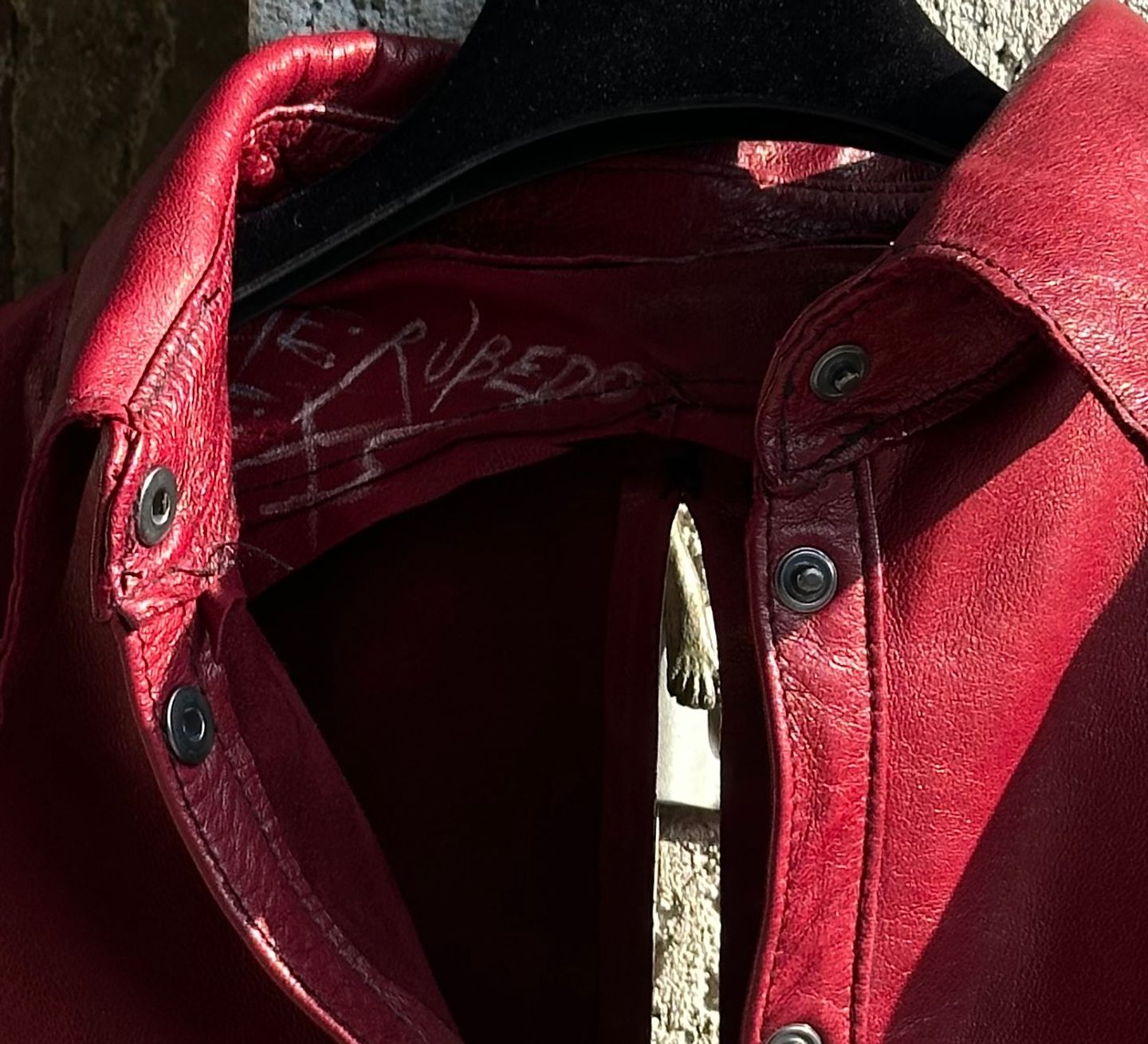 Interno del collo della giacca rossa, con una scritta a mano sulla pelle.