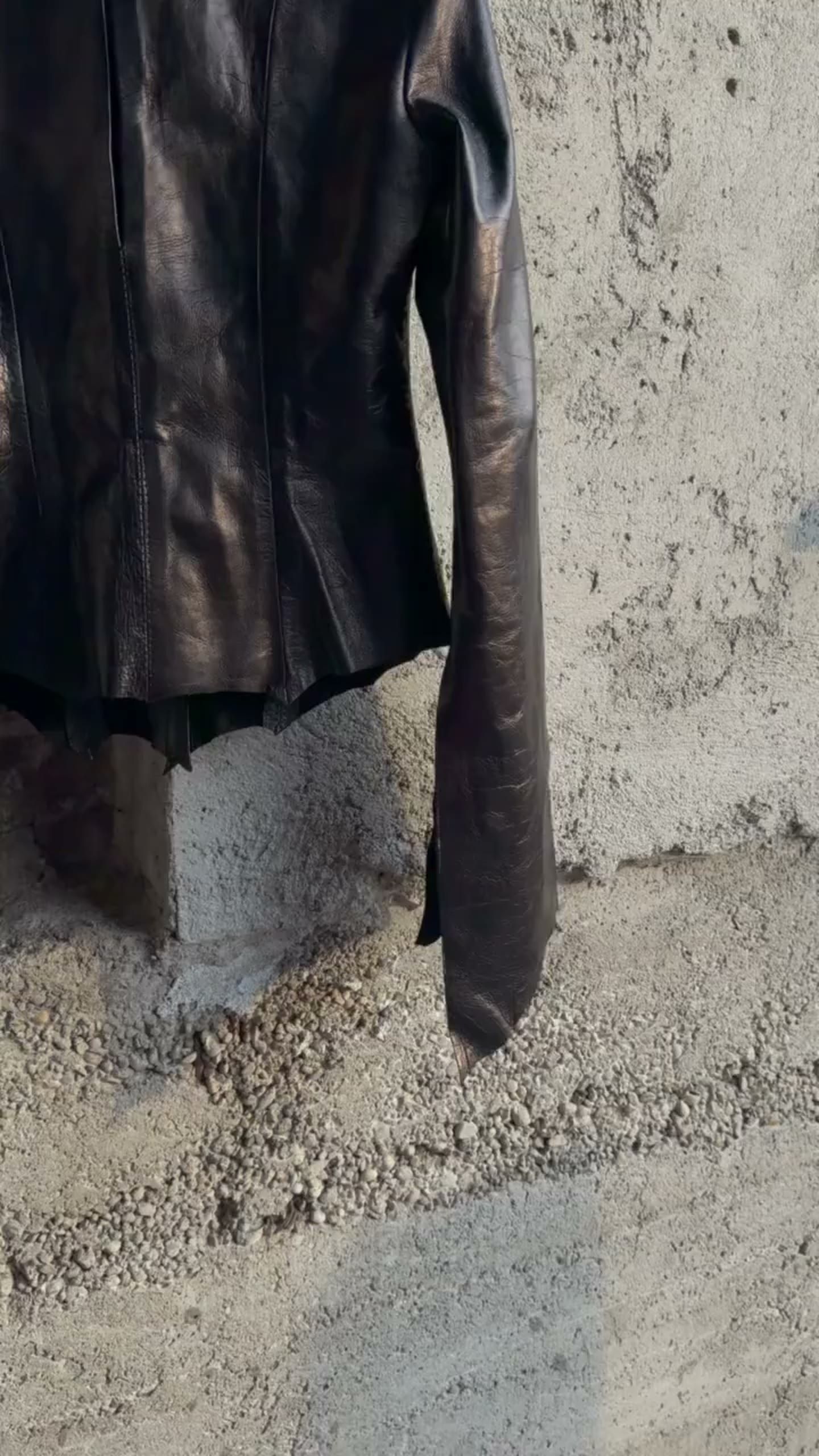 A black leather jacket hanging outside, moving in the wind.