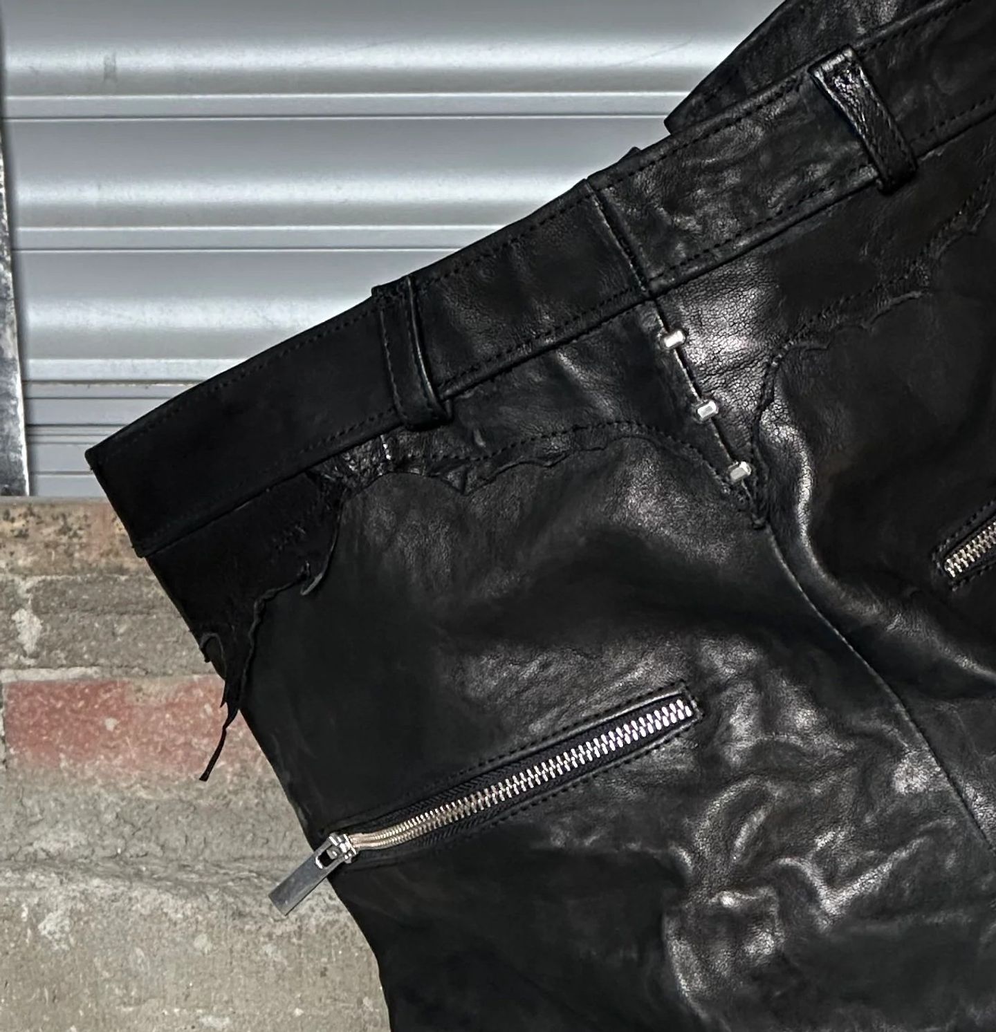 Cintura, passanti e zip a vista sui pantaloni in pelle nera.