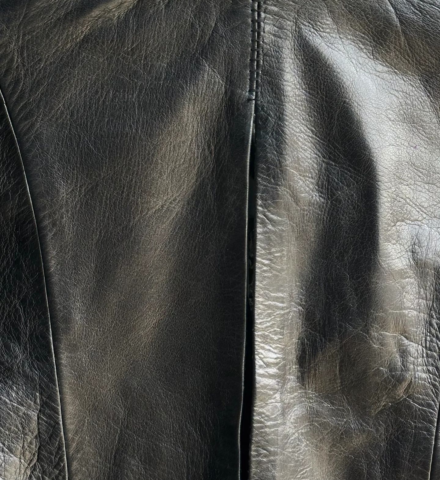 Cucitura centrale sulla schiena della camicia in pelle nera, con impuntura visibile.