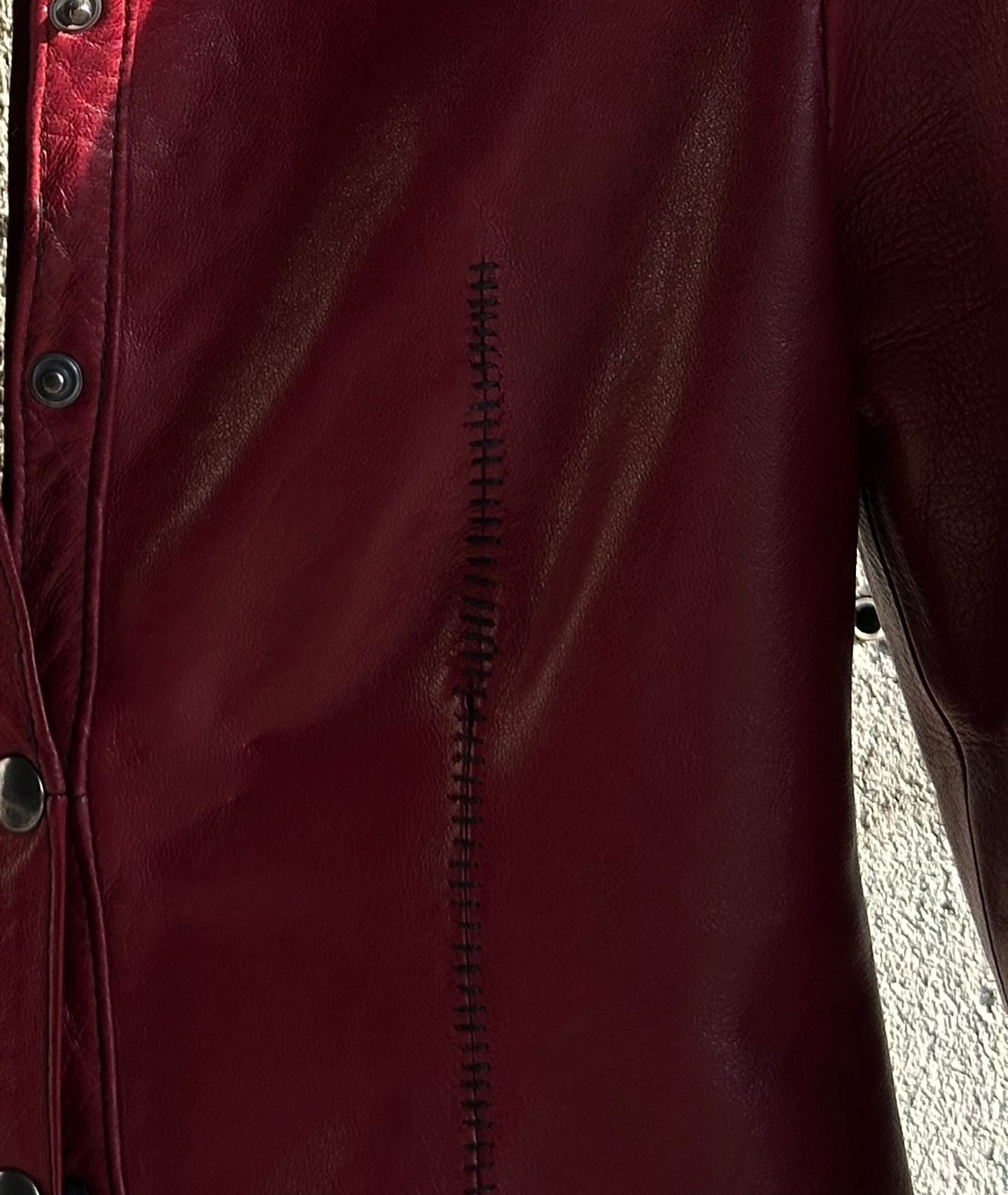 Dettaglio della cucitura a mano che scende lungo il davanti della giacca rossa.