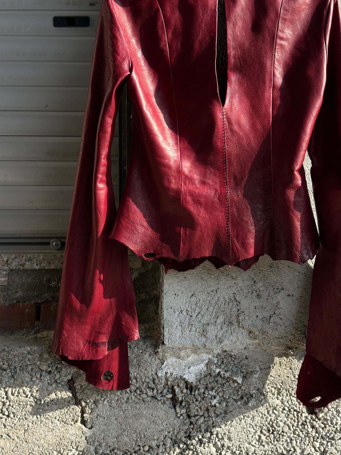 Dettaglio della camicia rossa, la manica lunga e l'orlo tagliato a punte.