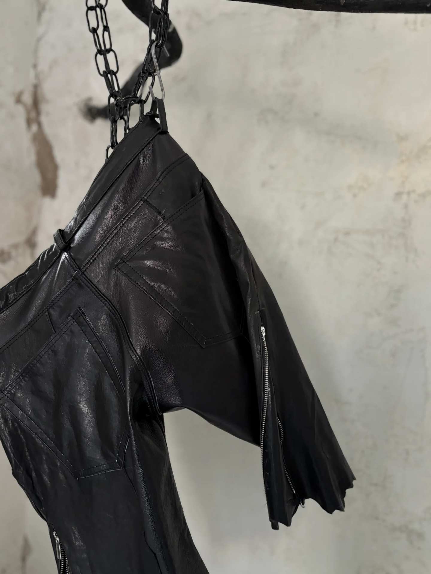 I pantaloncini in pelle appesi a una catena davanti a un muro chiaro.