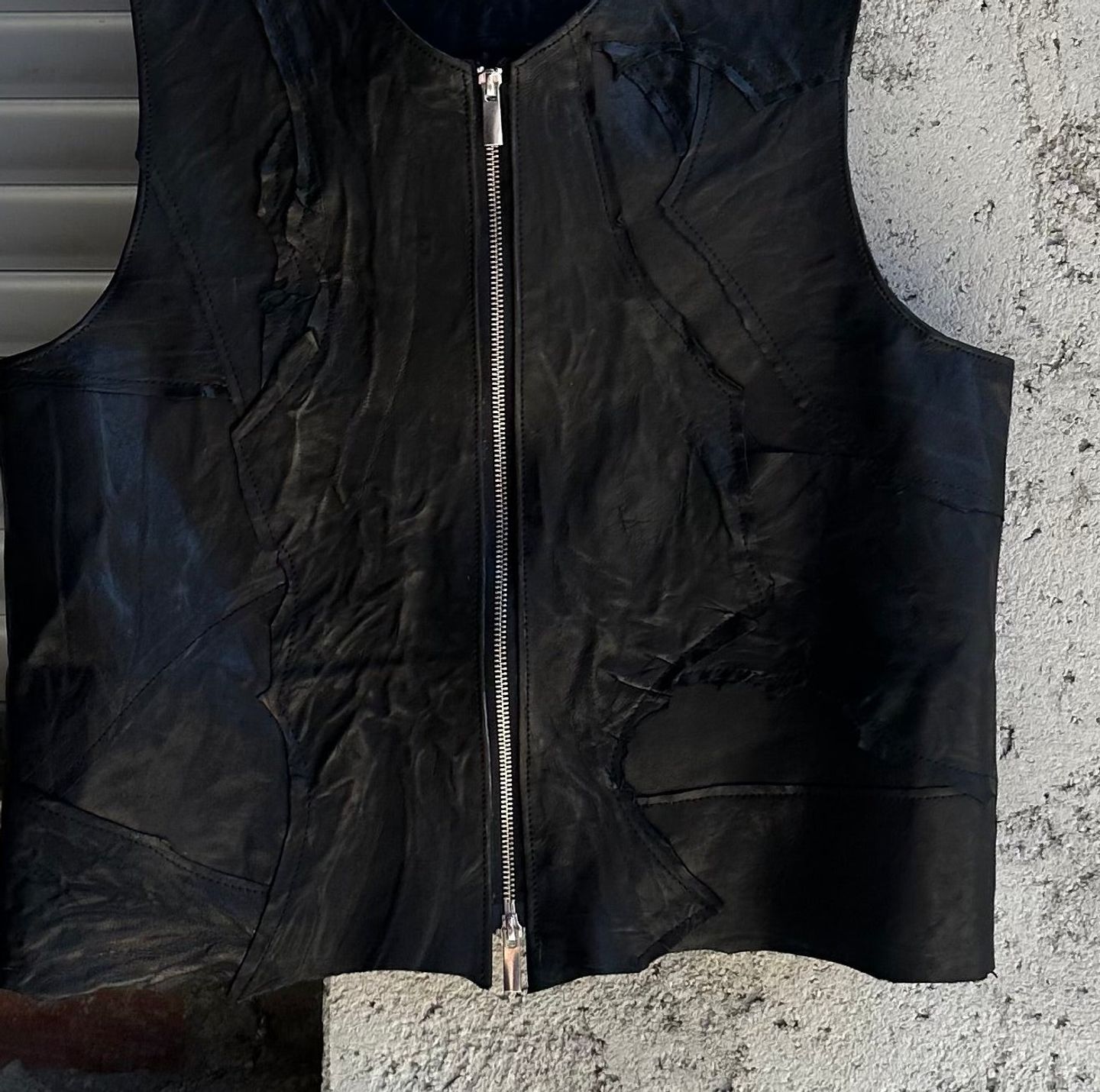 Pannelli di ritaglio cuciti sul davanti del gilet nero, attorno alla zip.
