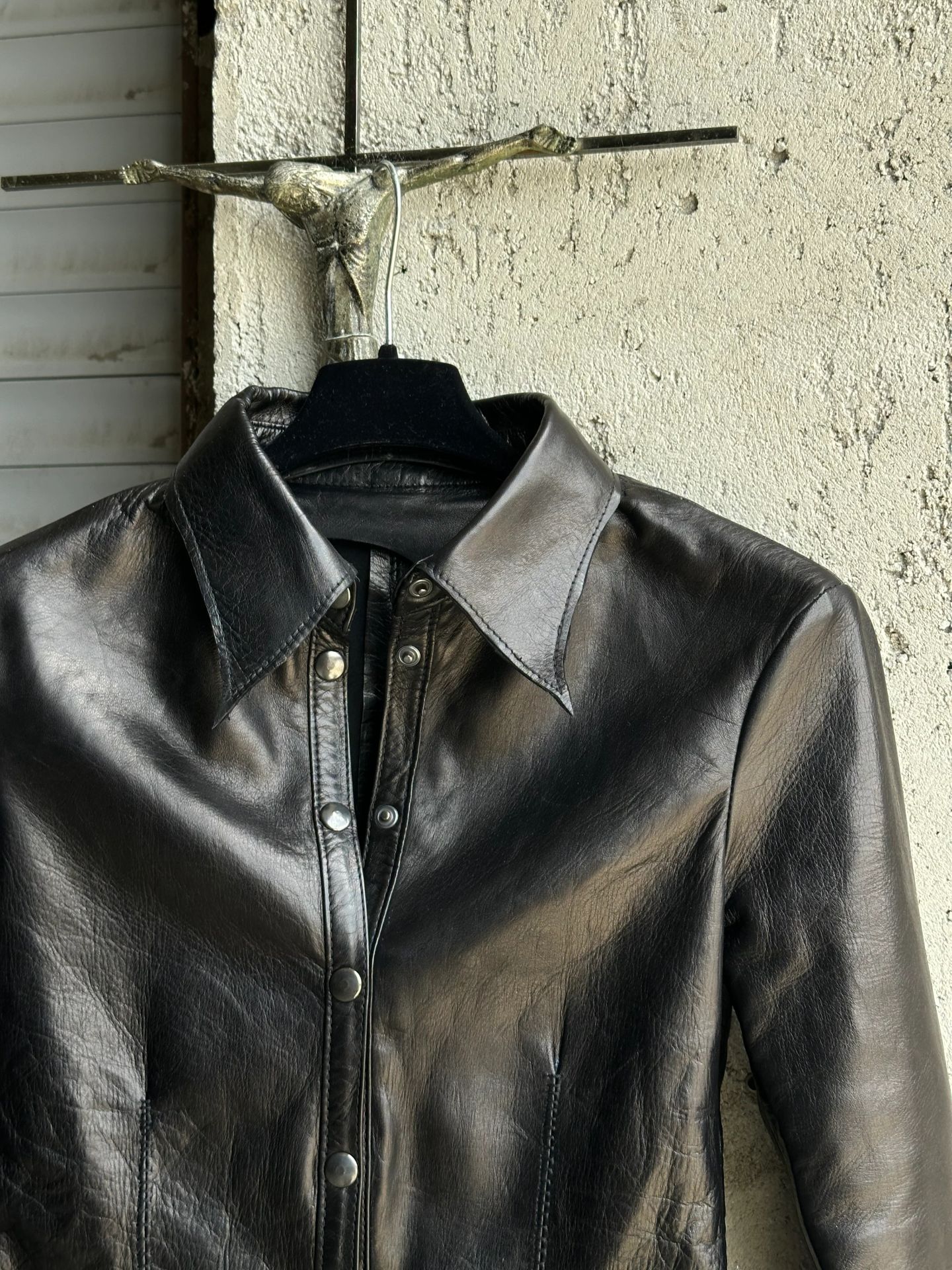 Dettaglio del collo e della chiusura della camicia in pelle nera.