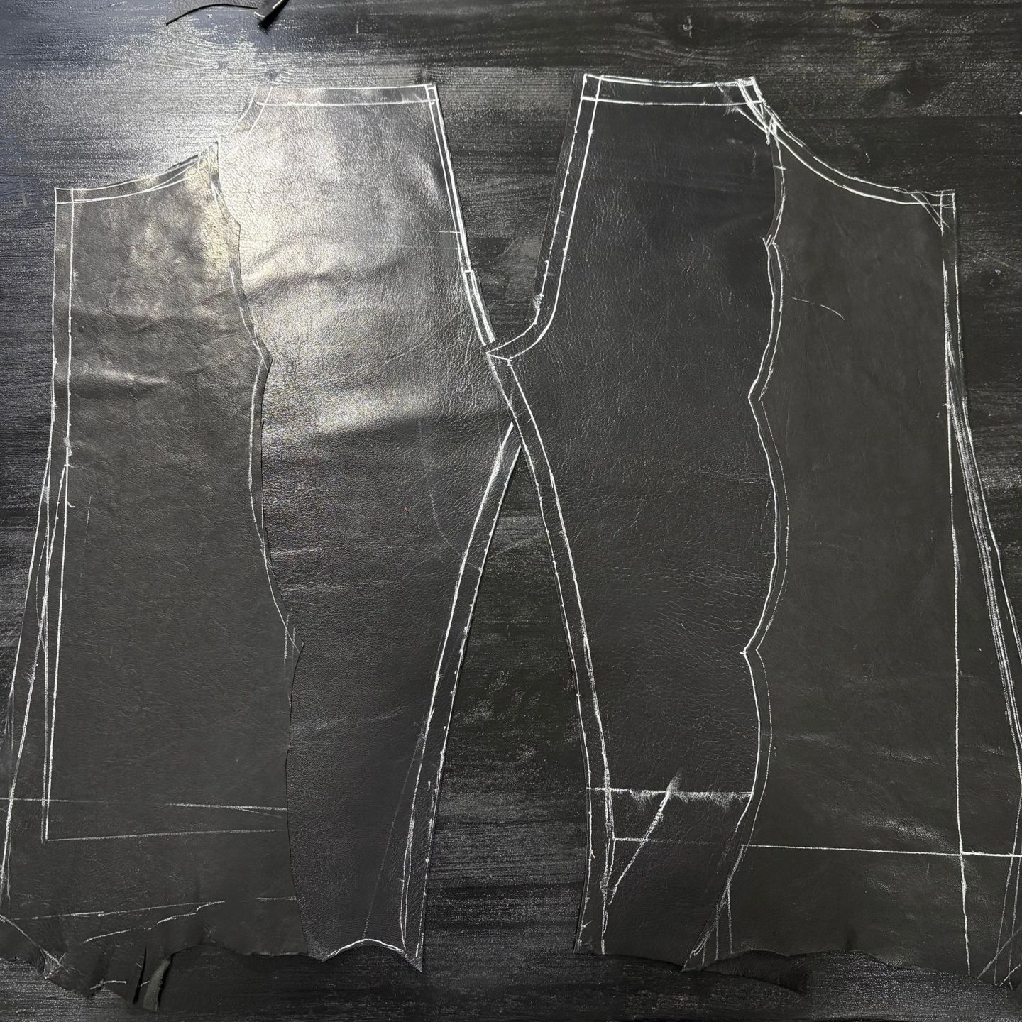 I pannelli dei pantaloni tagliati nella pelle nera, con i contorni ancora segnati a gesso.