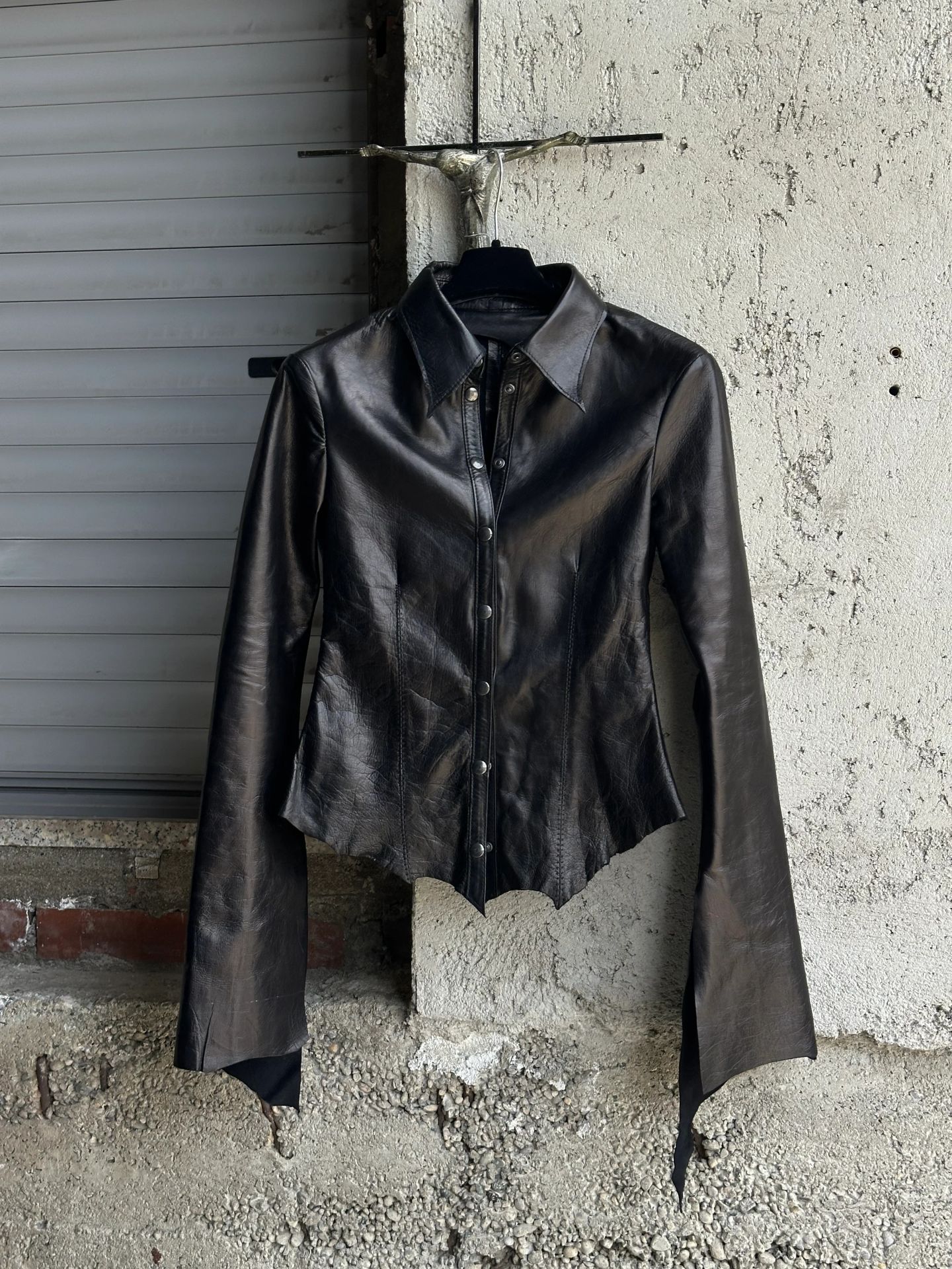 Retro della camicia in pelle nera appesa alla gruccia.