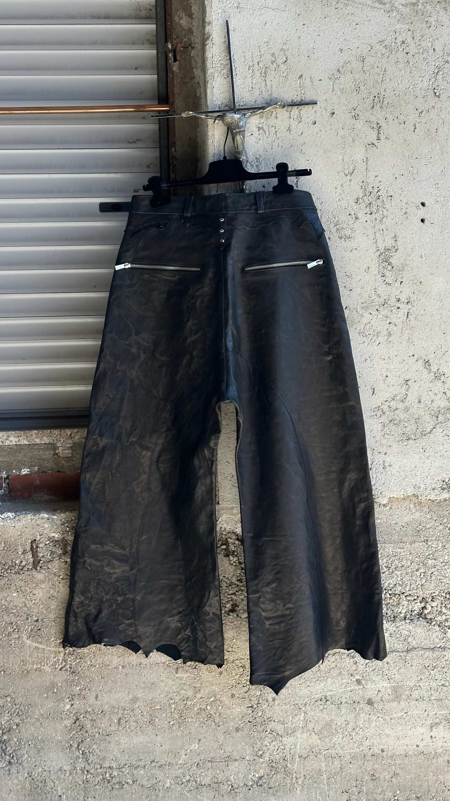 Gli stessi pantaloni in pelle nera visti da dietro, con due tasche con zip.