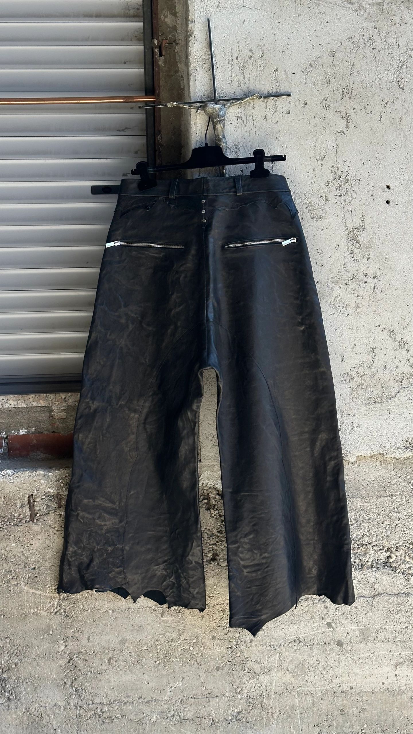 Gli stessi pantaloni in pelle nera visti da dietro, con due tasche con zip.