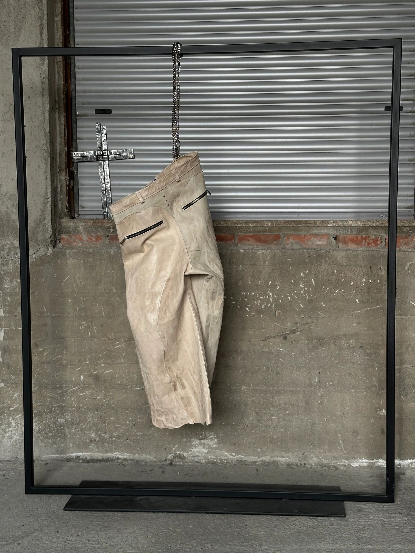 Dettaglio della cintura e delle tasche con zip sui pantaloni chiari.