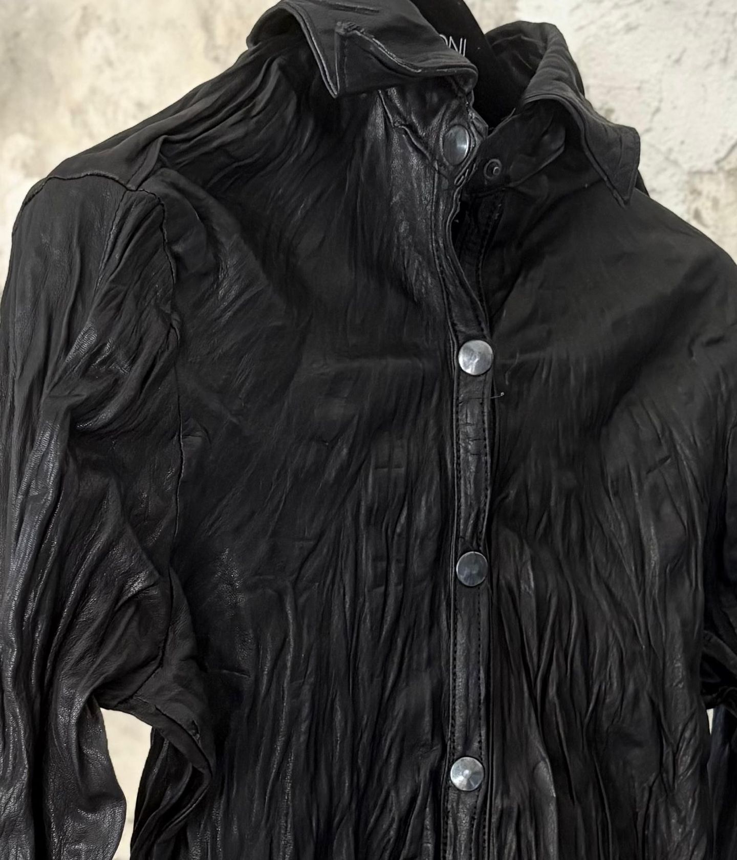 Collo e bottoni a pressione della camicia nera, con la pelle increspata.
