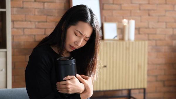Grieving woman holding a cremation urn while mourning the loss of a loved one