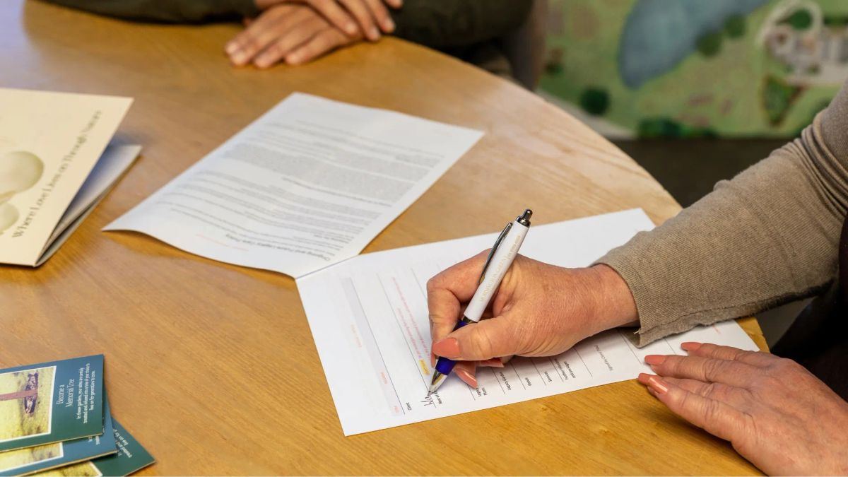 Close-up of a person signing a pet loss counselling form during a consultation session.