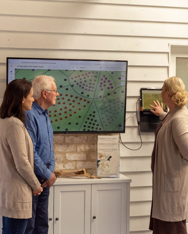 Legacy planer staff member showing garden plot map on screen to two visitors.