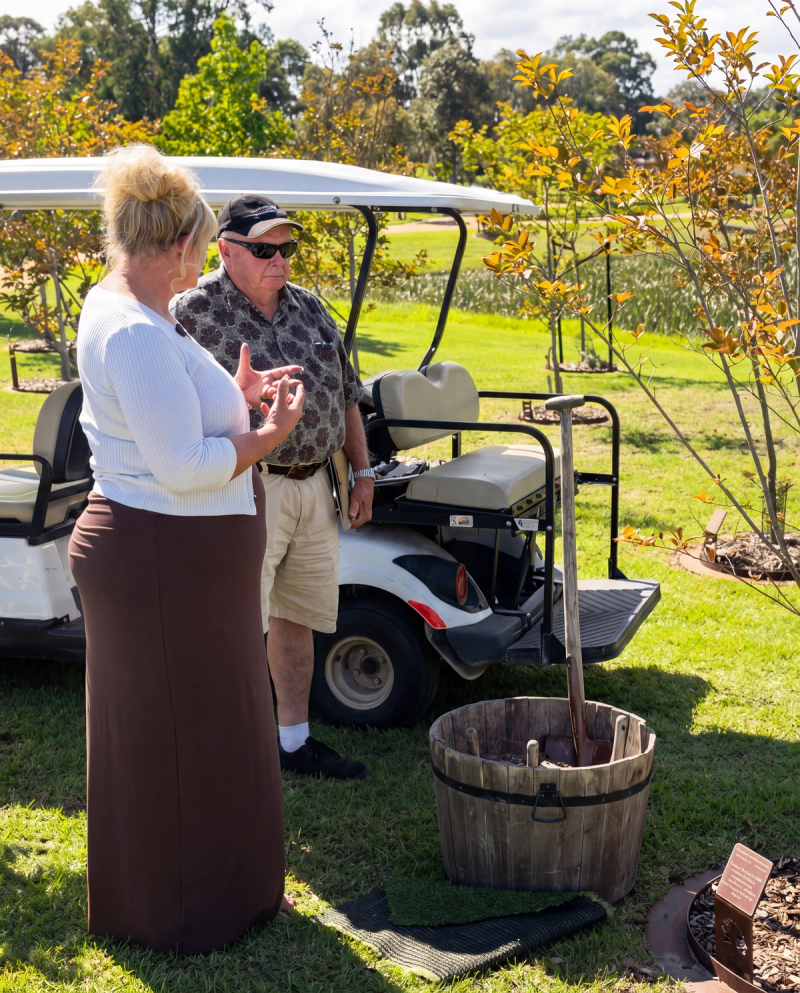 Legacy planer staff and visitor chatting beside a memorial tree in the garden.
