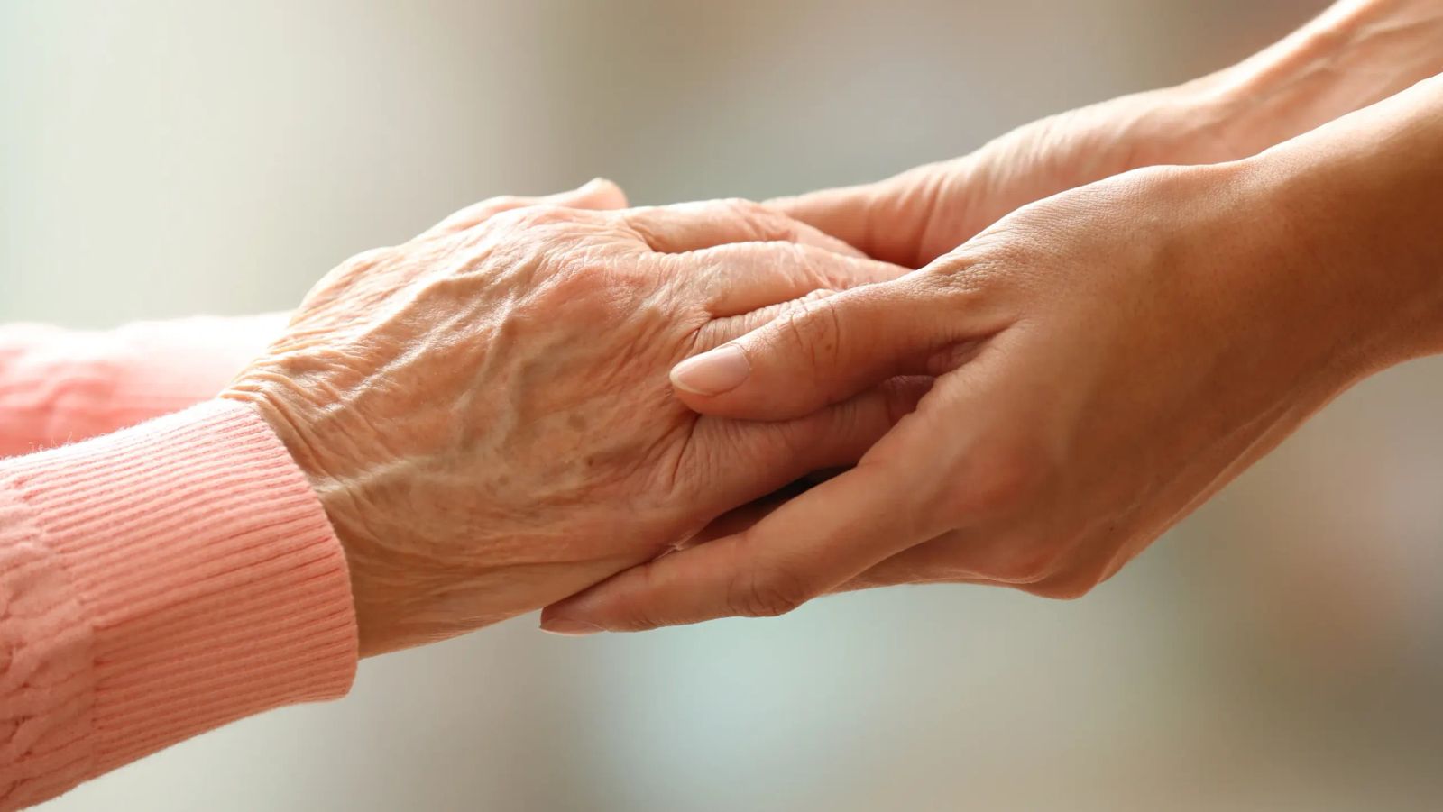 Adult child holding her parent's hand for comfort after a parent dies in Australia