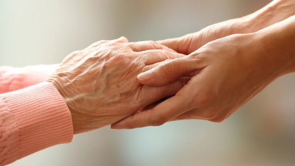 Adult child holding her parent's hand for comfort after a parent dies in Australia