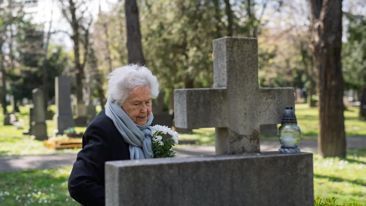 Australian woman visiting her late parent's grave with fresh flowers