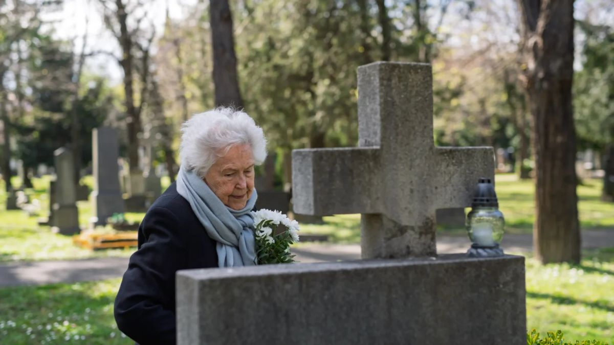 Australian woman visiting her late parent's grave with fresh flowers
