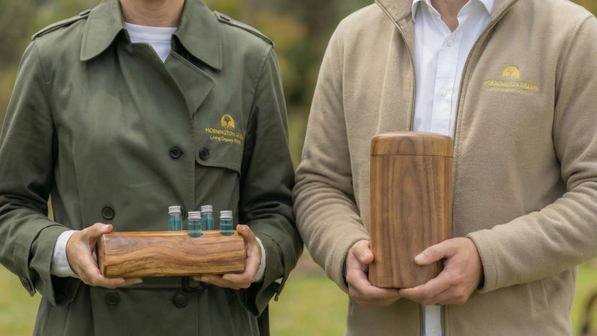 Mornington Green Living Legacy Gardens staff holding a wooden cremation urn and ash infusion vials outdoors