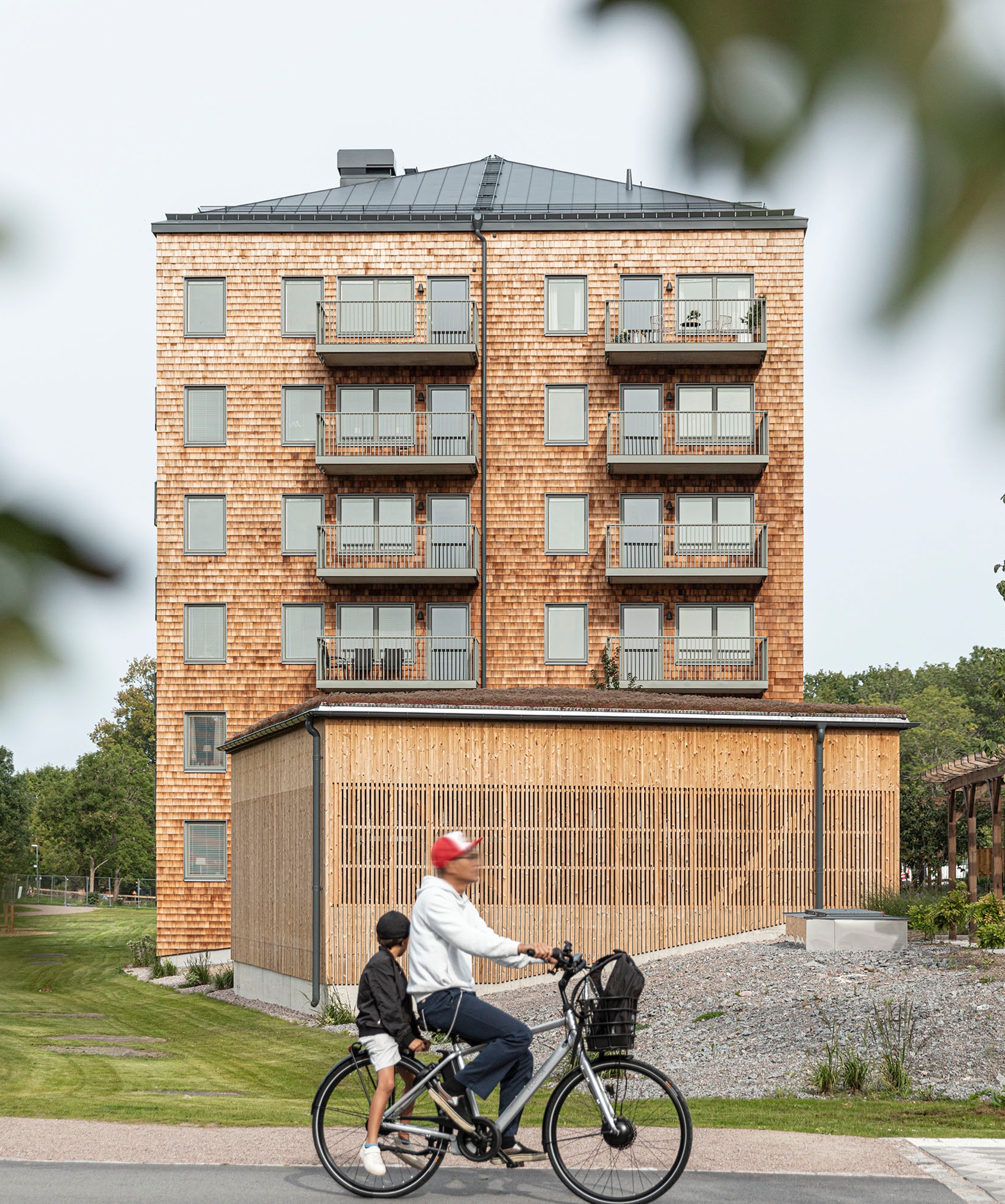 Parkhusen, punkthus. Fasad med cederspån. Cyklist i förgrunden.
