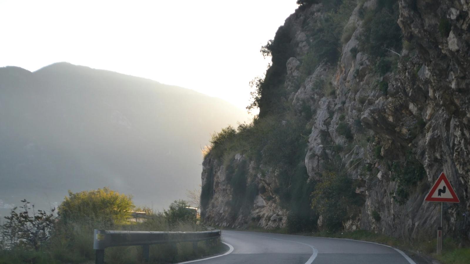 A car driving down a mountain road next to a cliff