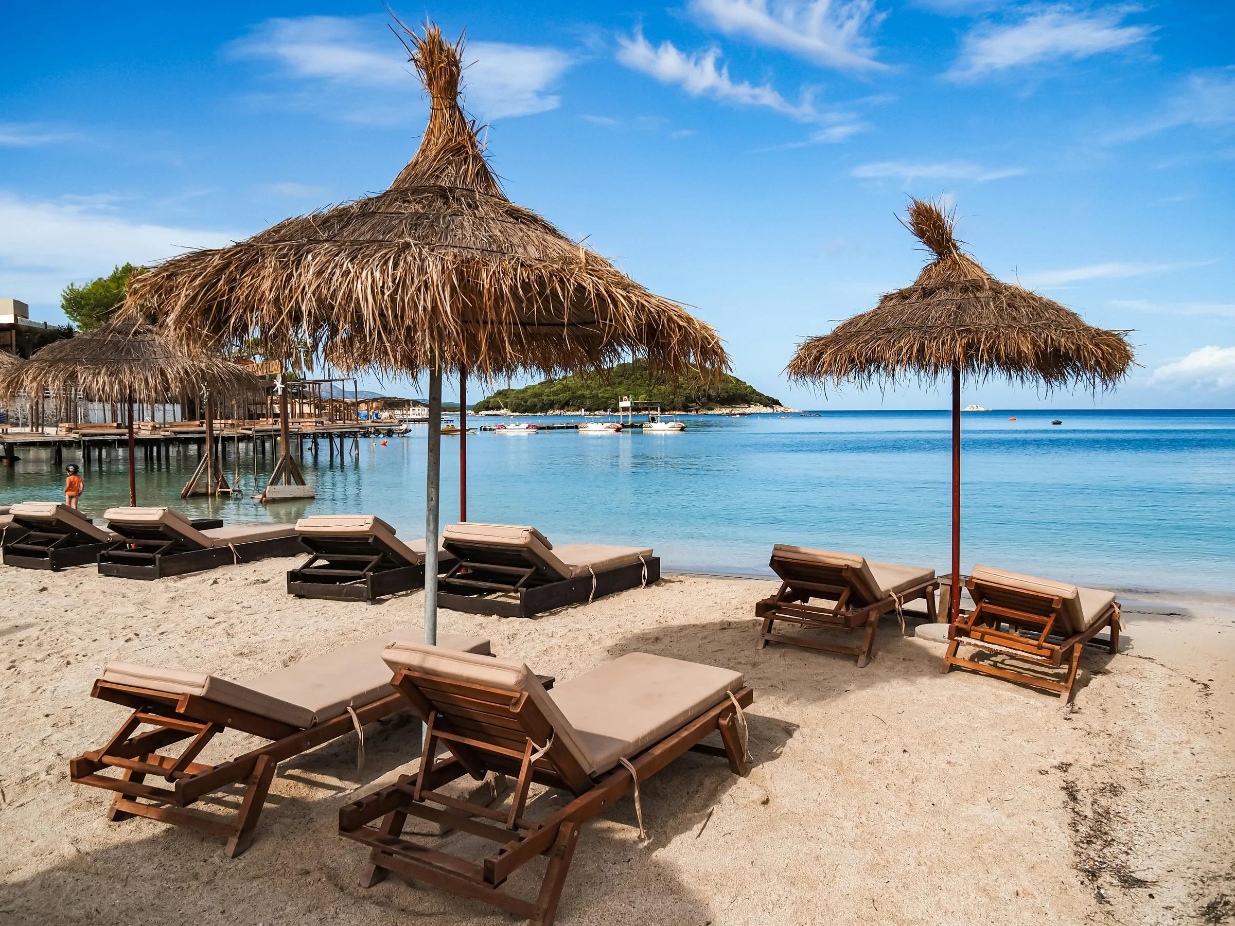 A sandy beach with lounge chairs and straw umbrellas