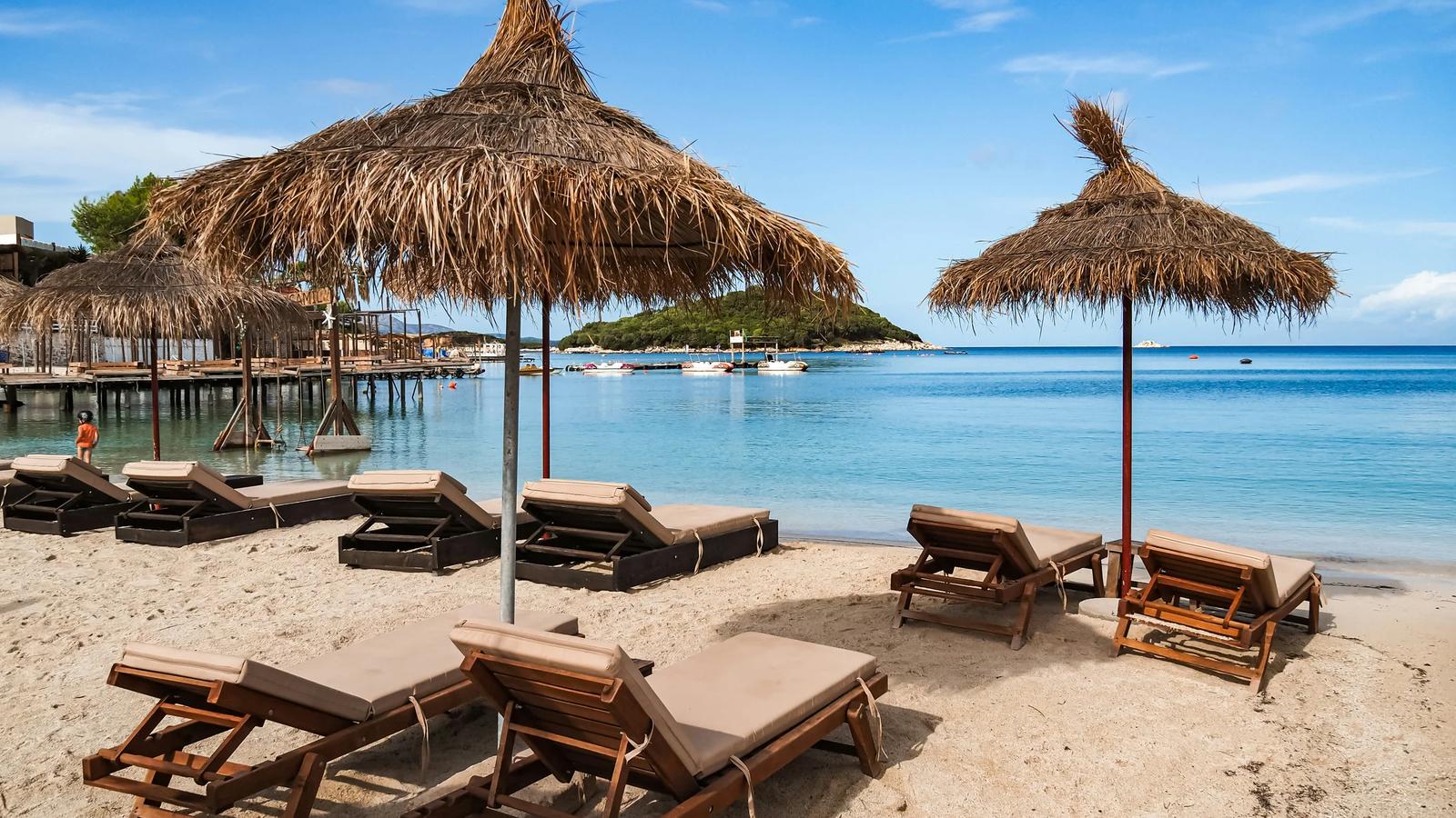 A sandy beach with lounge chairs and straw umbrellas