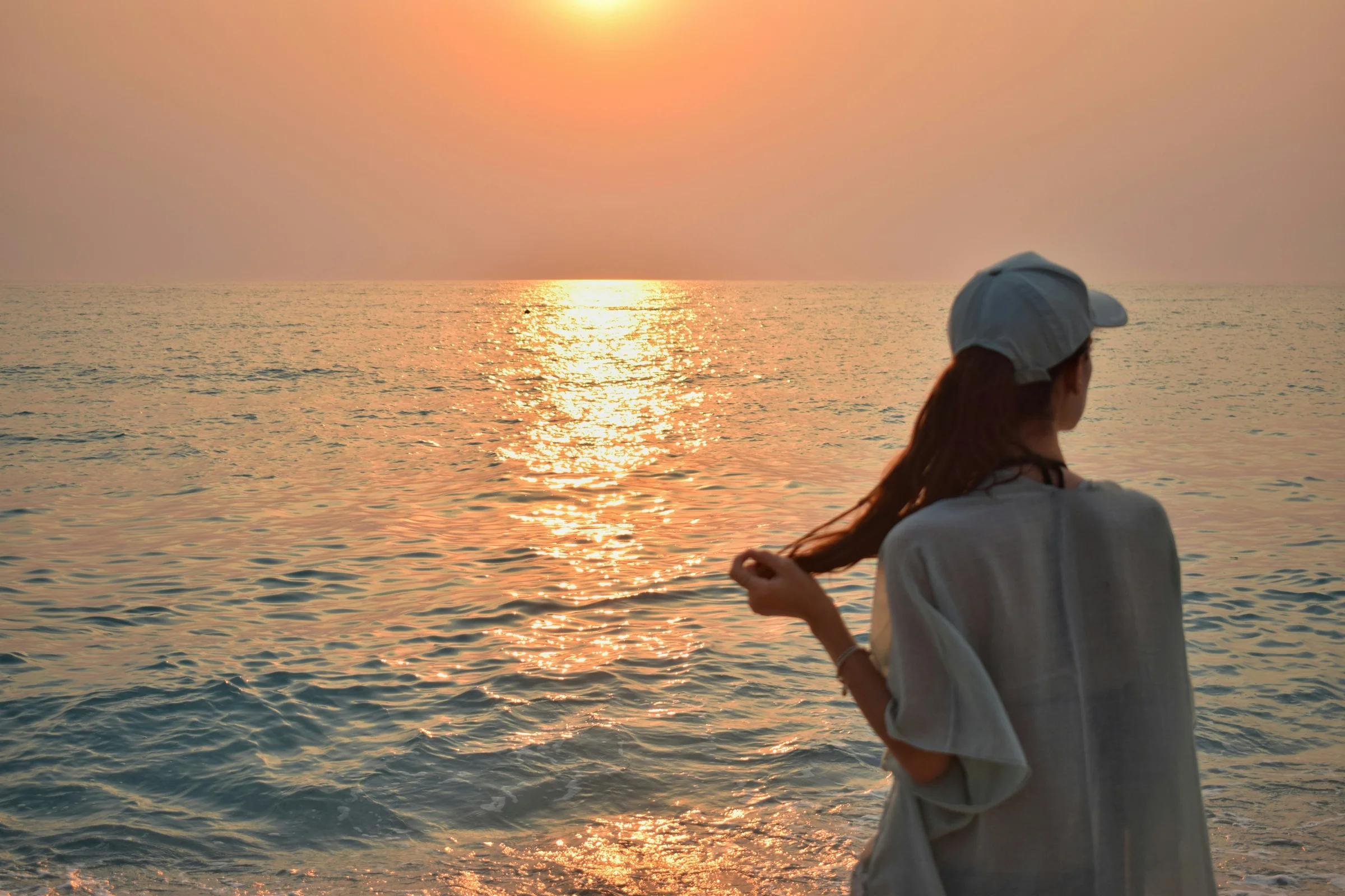 a woman standing on a beach next to the ocean