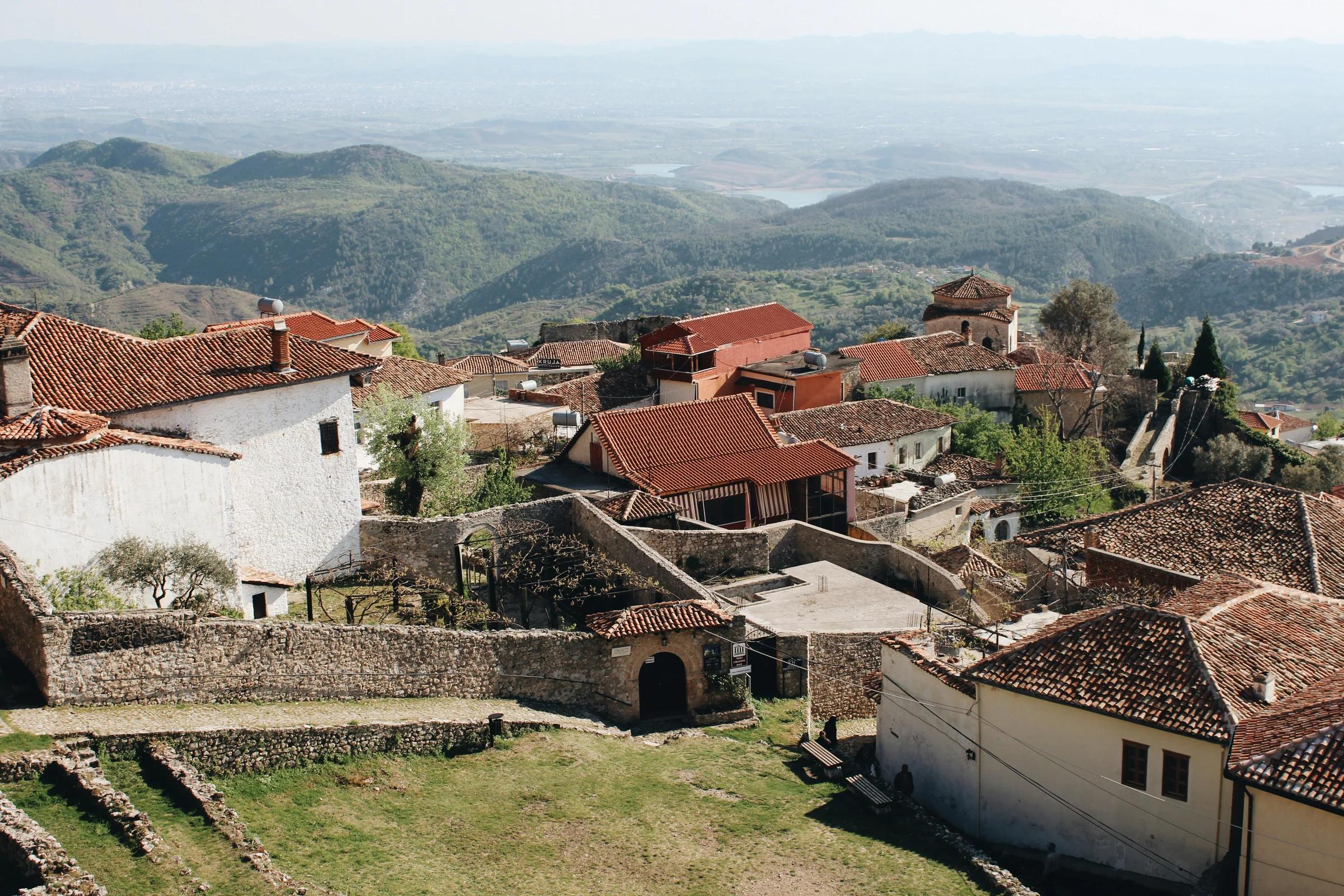 white and brown concrete houses near green grass field during daytime