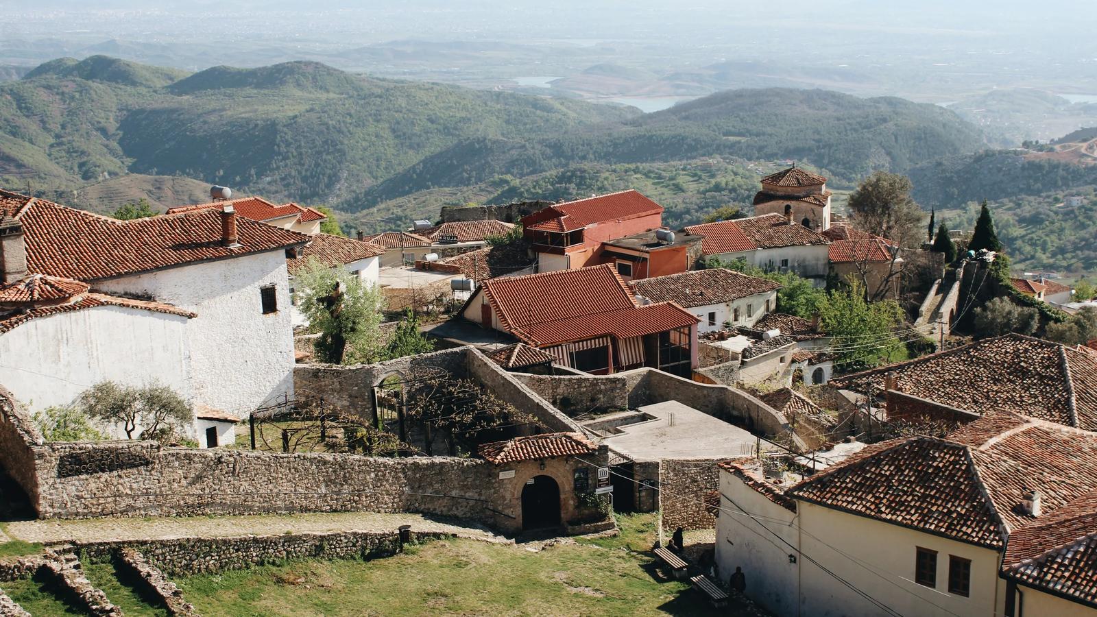 white and brown concrete houses near green grass field during daytime