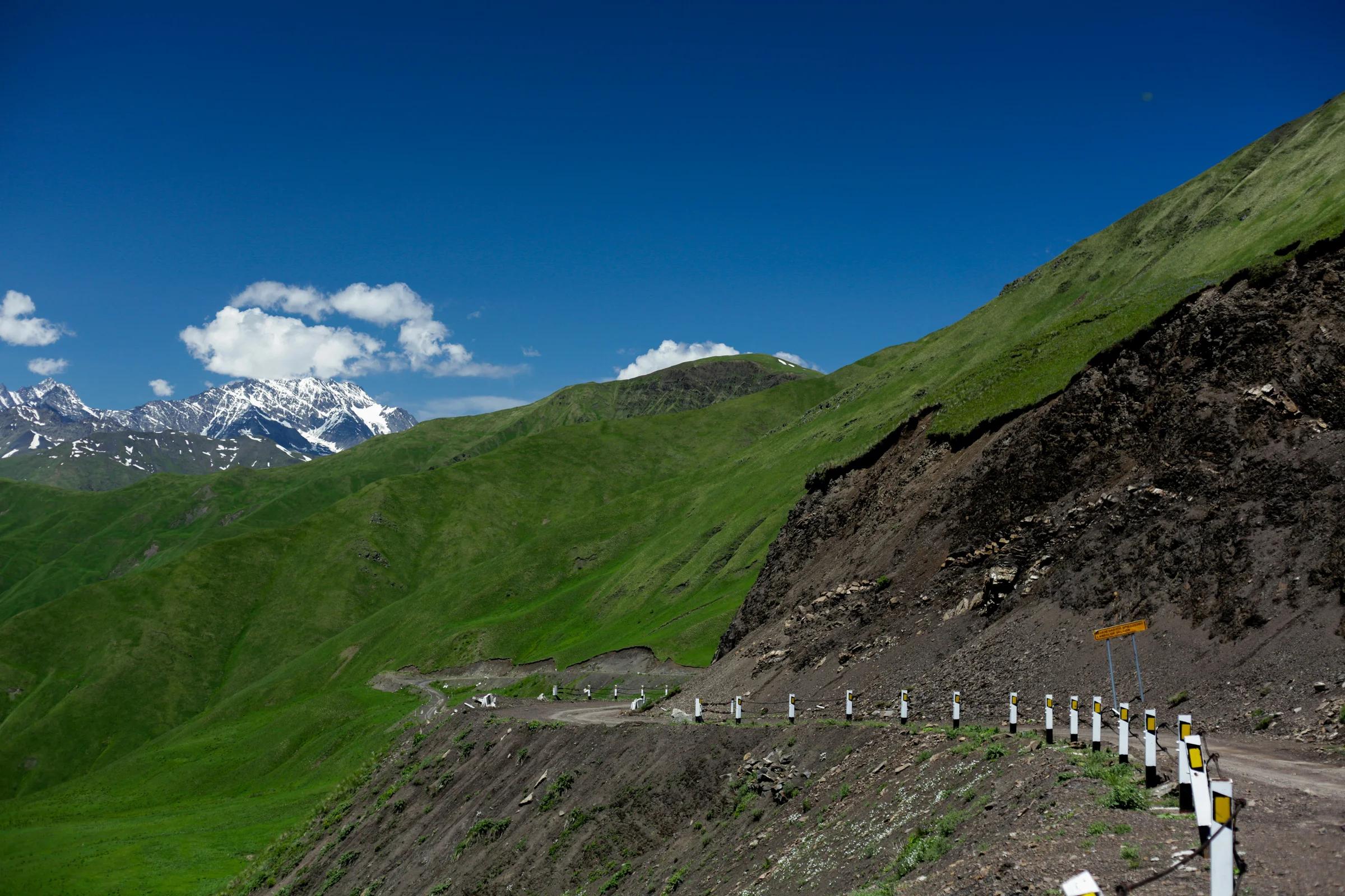 A road going up a hill with a mountain in the background