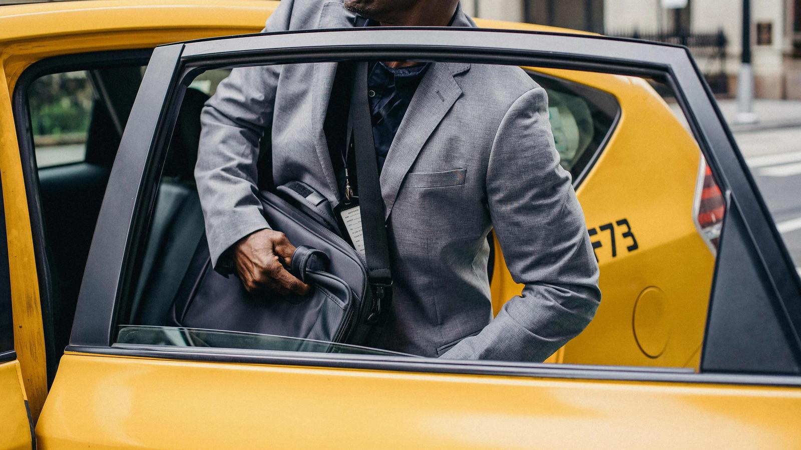 Урожай черный человек сидит в машине такси, припаркованной на улице