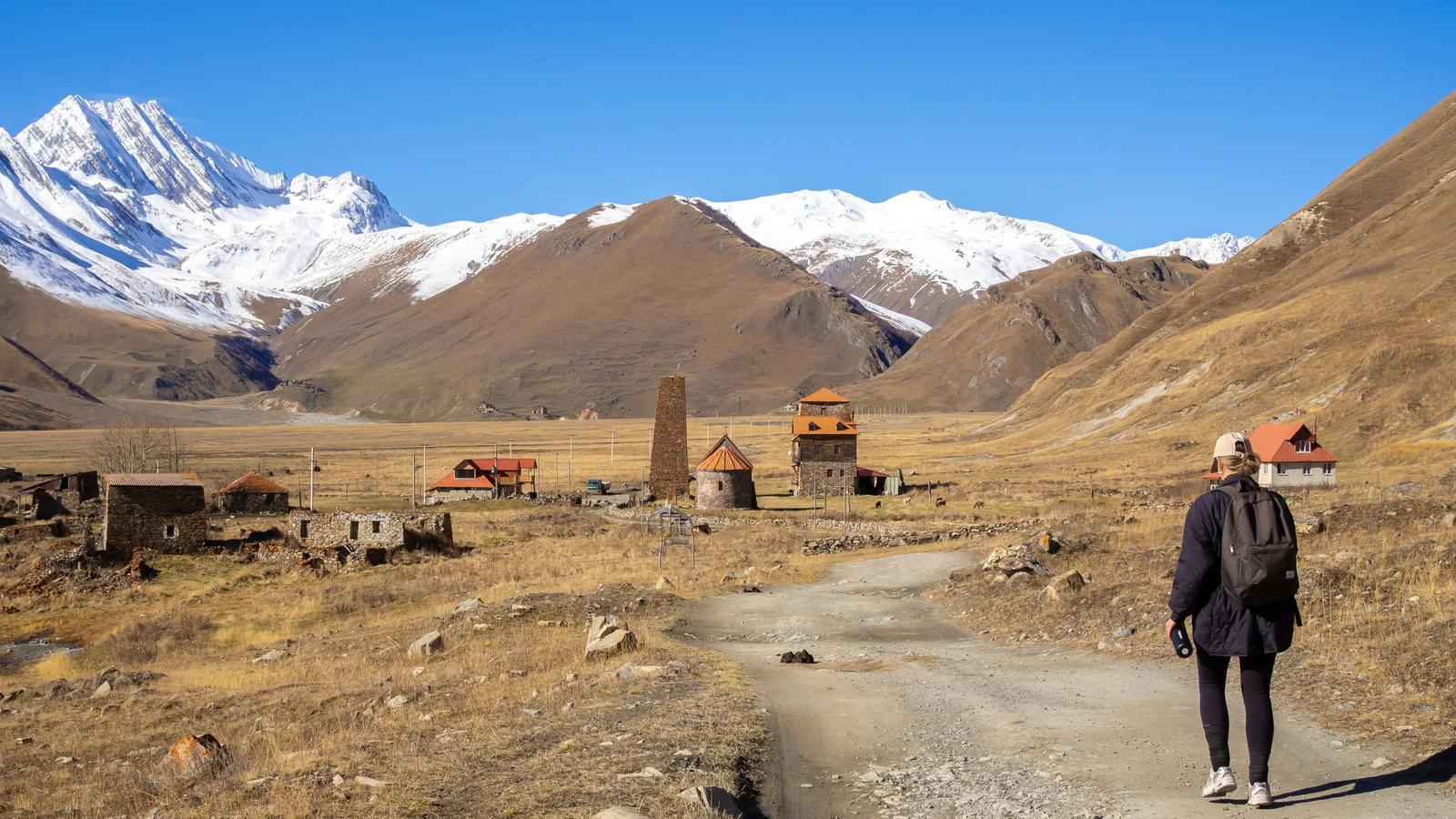 A man walking down a dirt road in the mountains