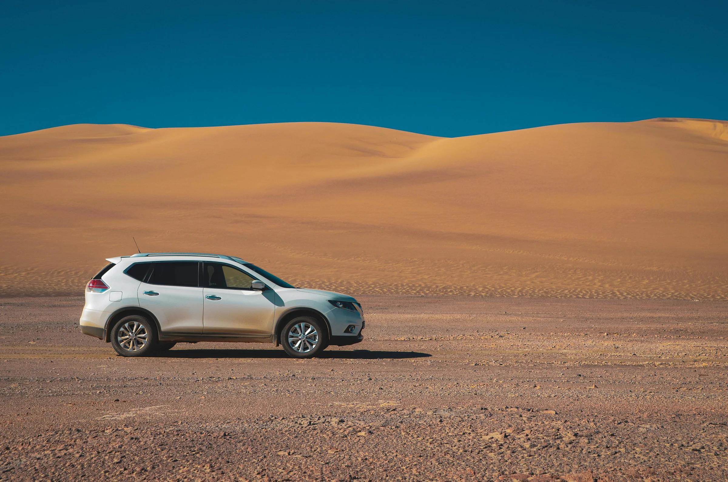 Белый внедорожник на пустынной дороге под голубым небом