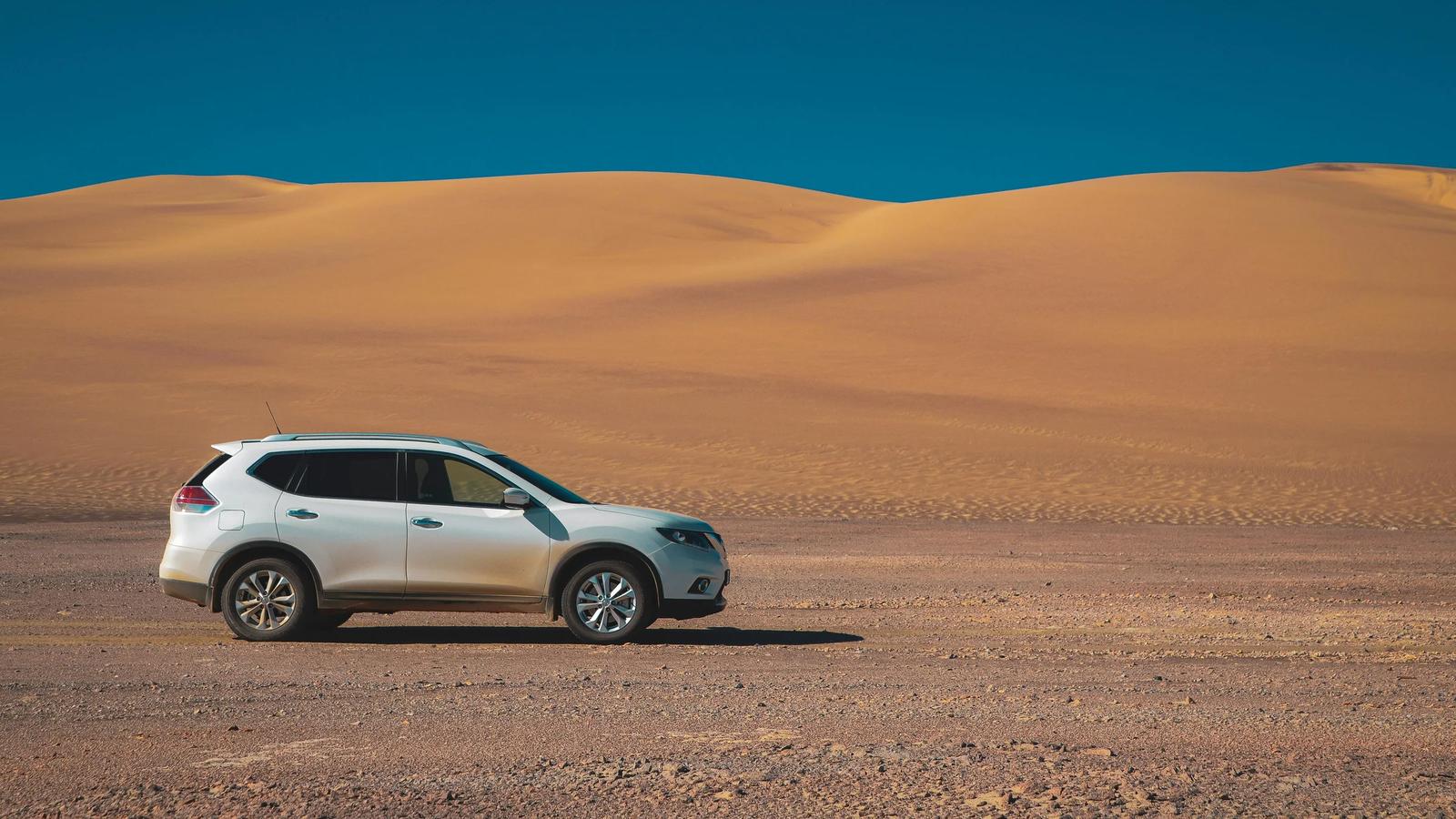 Белый внедорожник на пустынной дороге под голубым небом