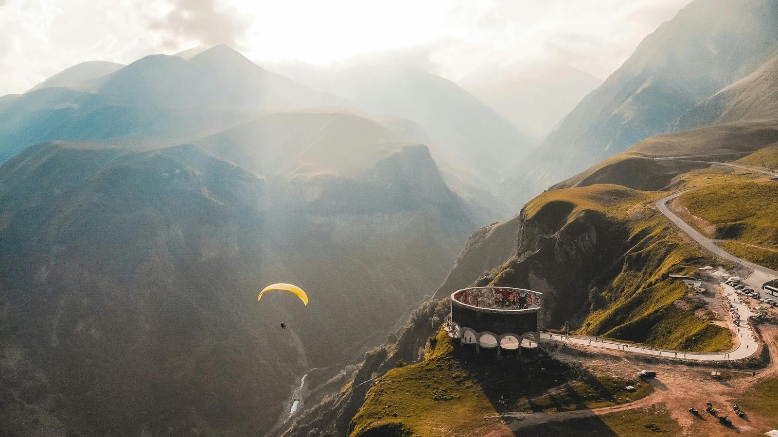 person paragliding on mountain cliff during daytime