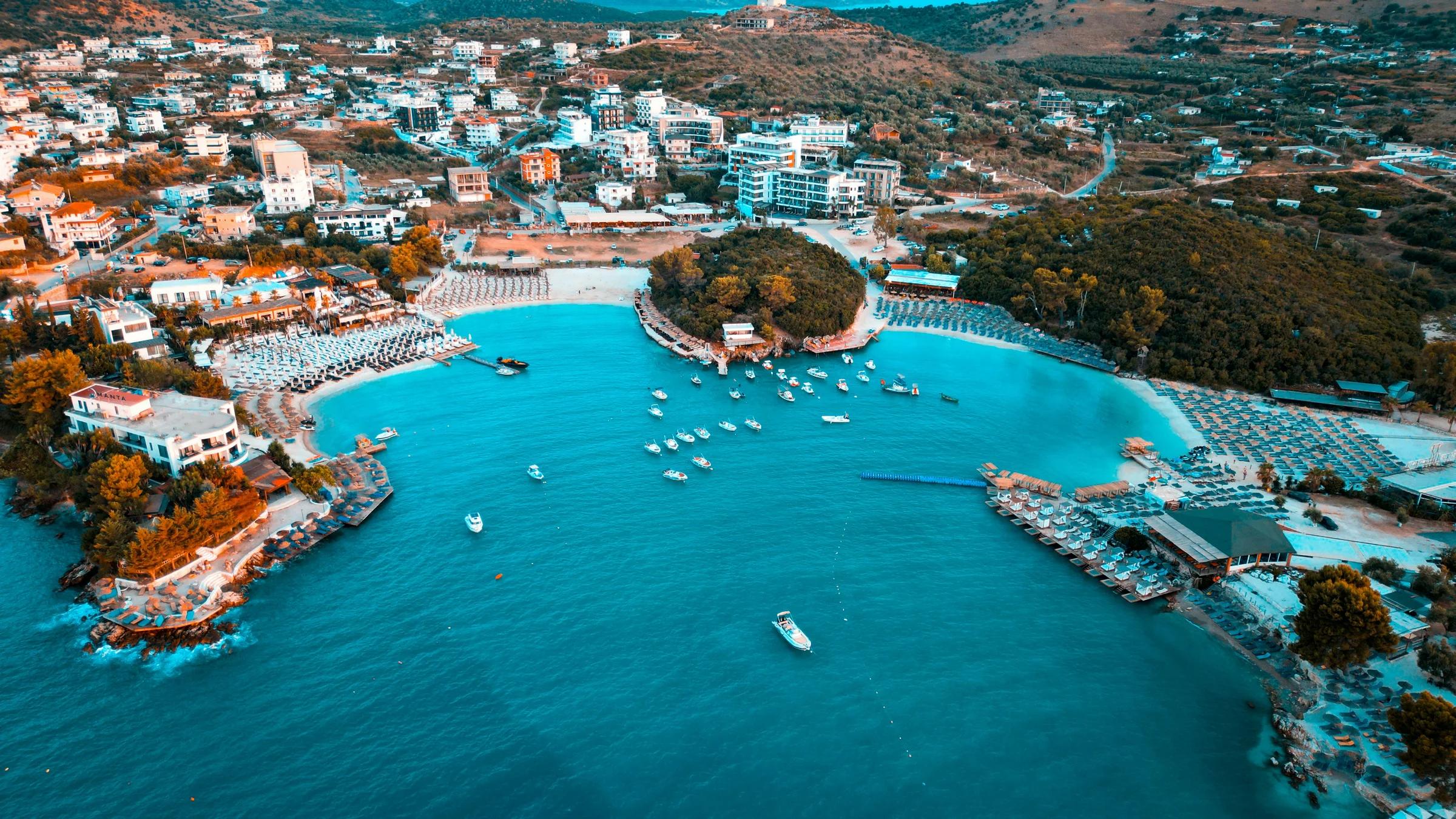 Coastal town with boats in turquoise bay and buildings.
