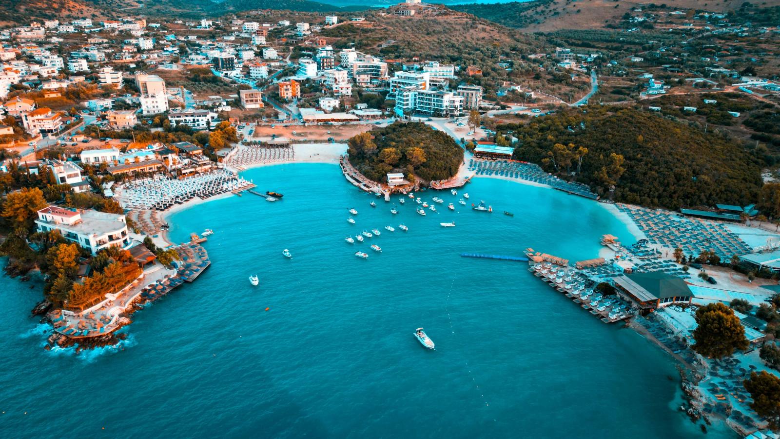 Coastal town with boats in turquoise bay and buildings.