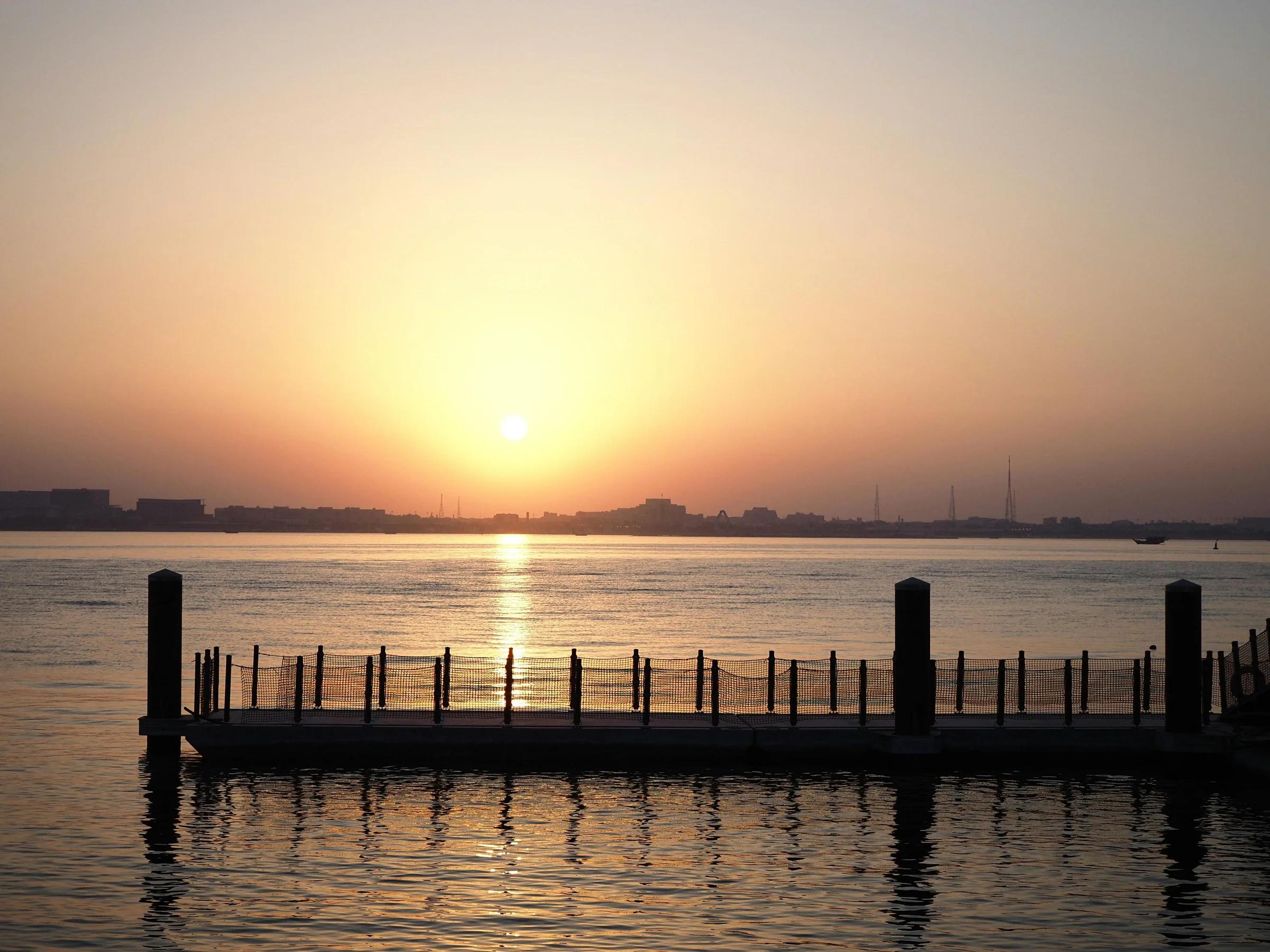 Безмятежный закат над пирсом на набережной в Дохе