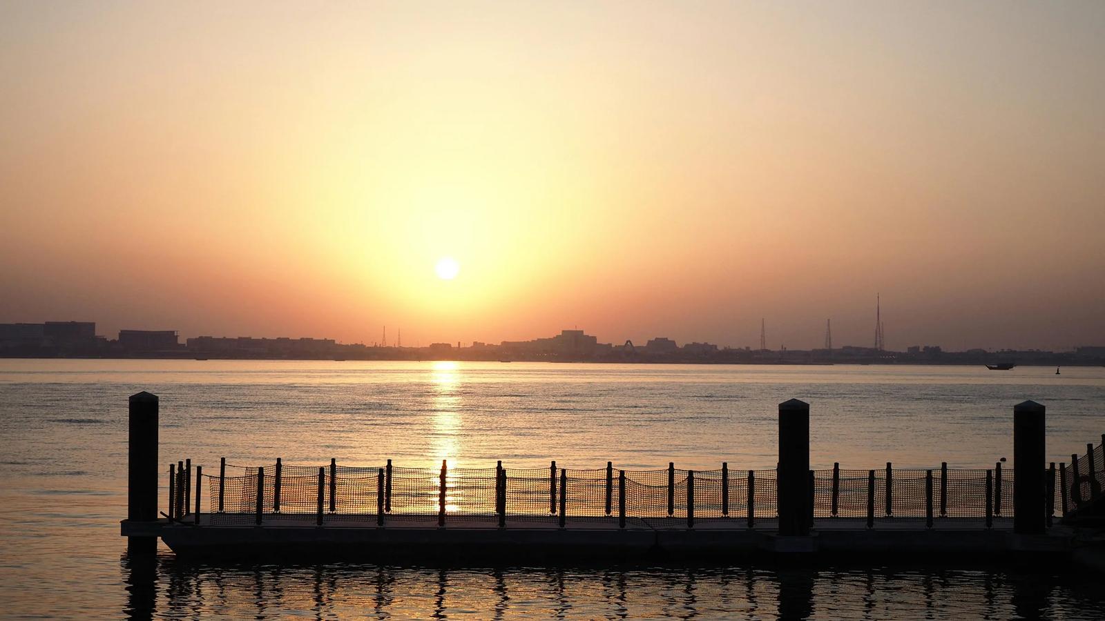 Безмятежный закат над пирсом на набережной в Дохе