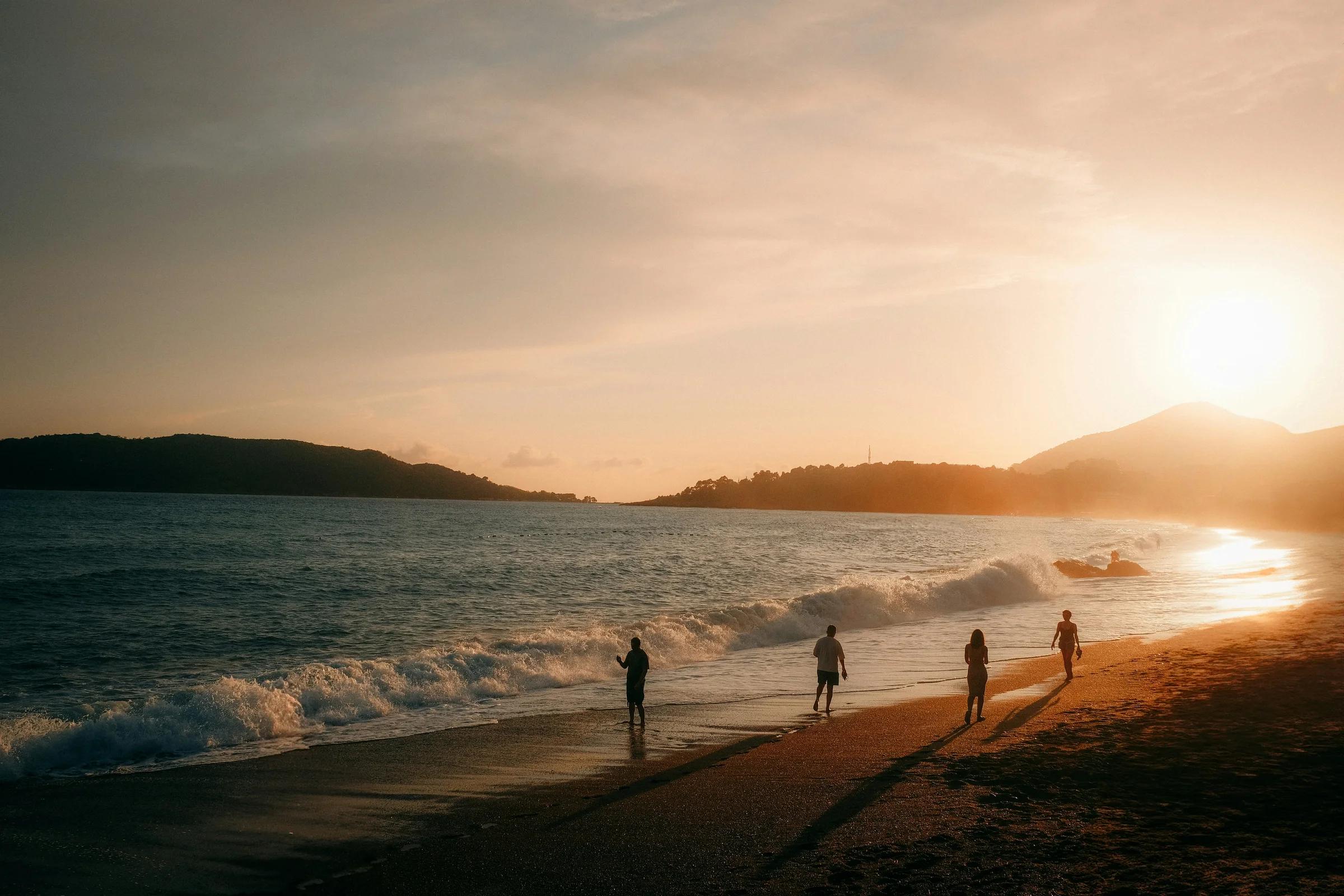 People walking on a beach at sunset